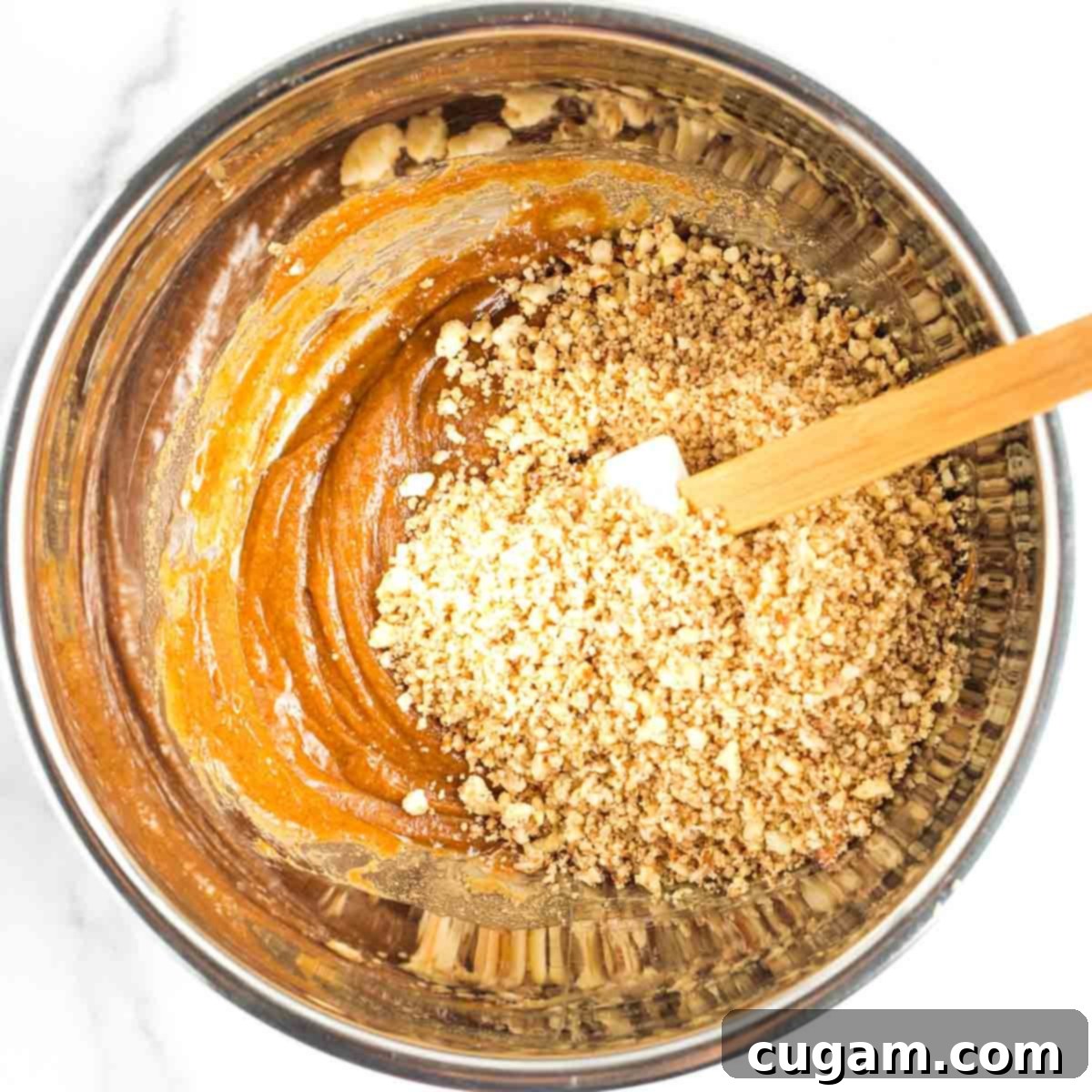 Decadent Vegan Almond Macaroons Enrobed in Chocolate 8 Stirring wet ingredients with coarsely chopped nuts in a metal mixing bowl.