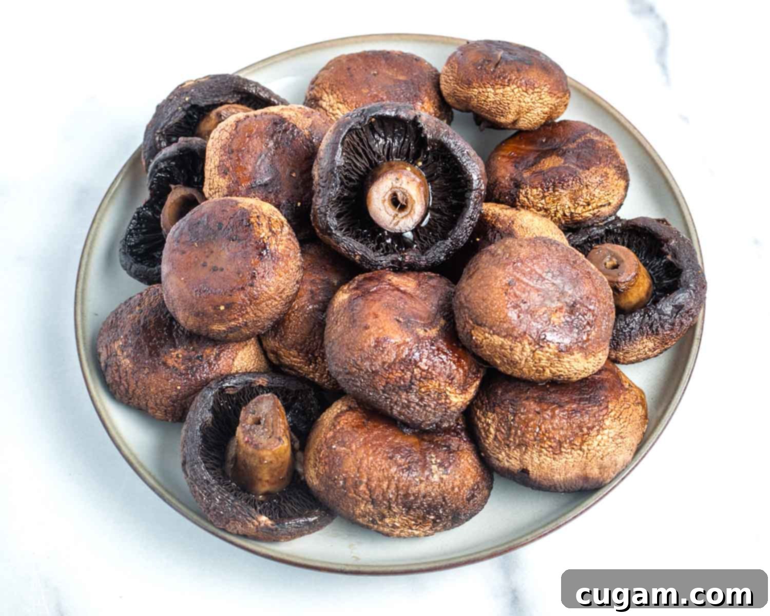 Bowl filled with whole roasted portobello mushrooms, ready for sauce.
