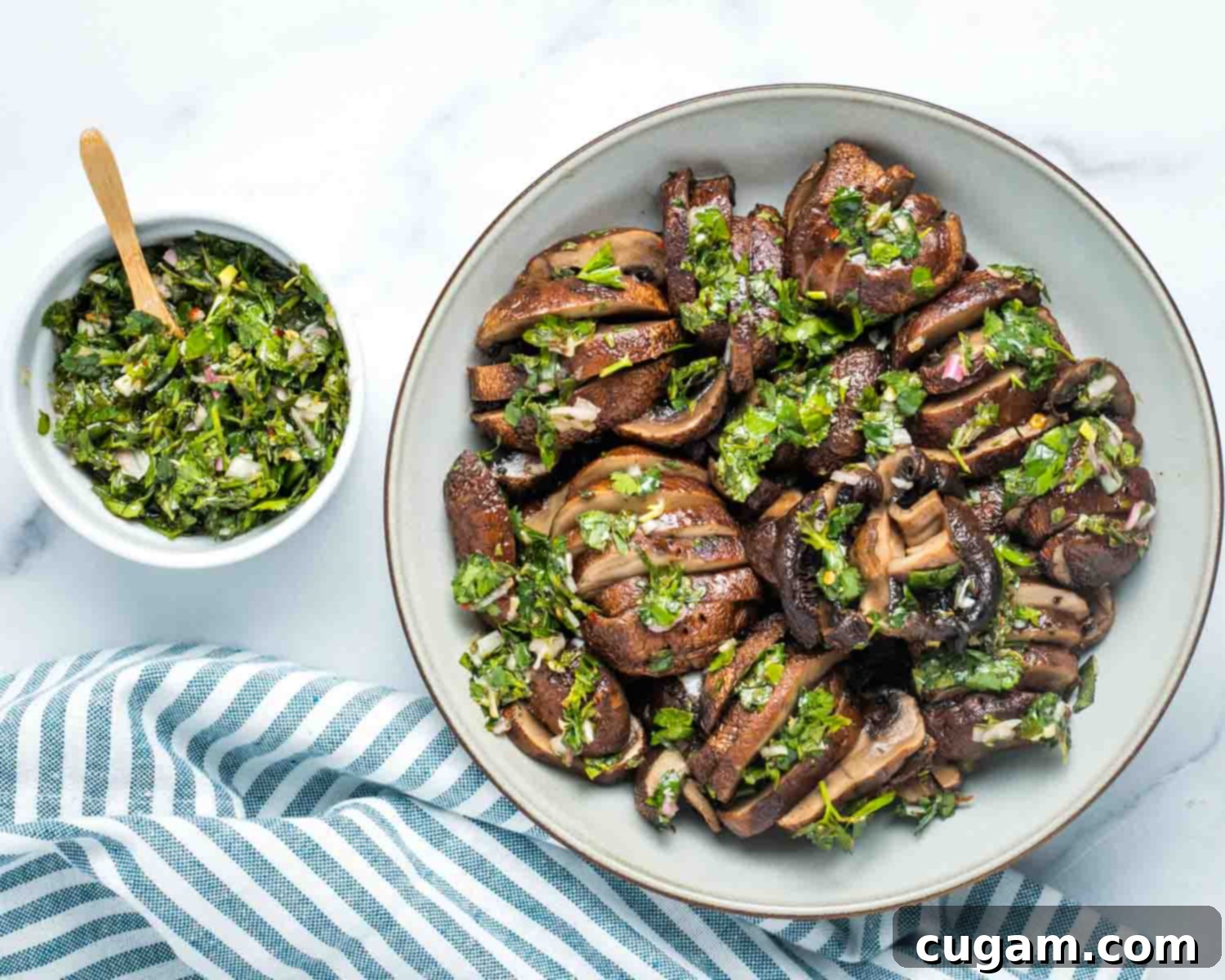 Portobello mushrooms, roasted and sliced, covered in vibrant green chimichurri, presented as a salad.