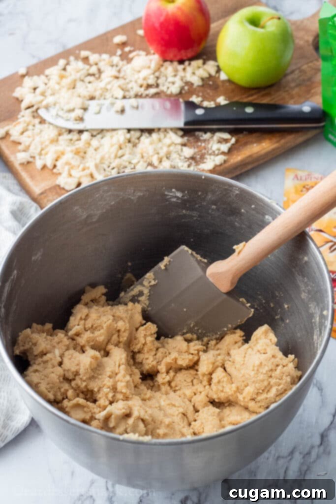 Raw caramel apple cookie dough in metal bowl with rubber spatula. 