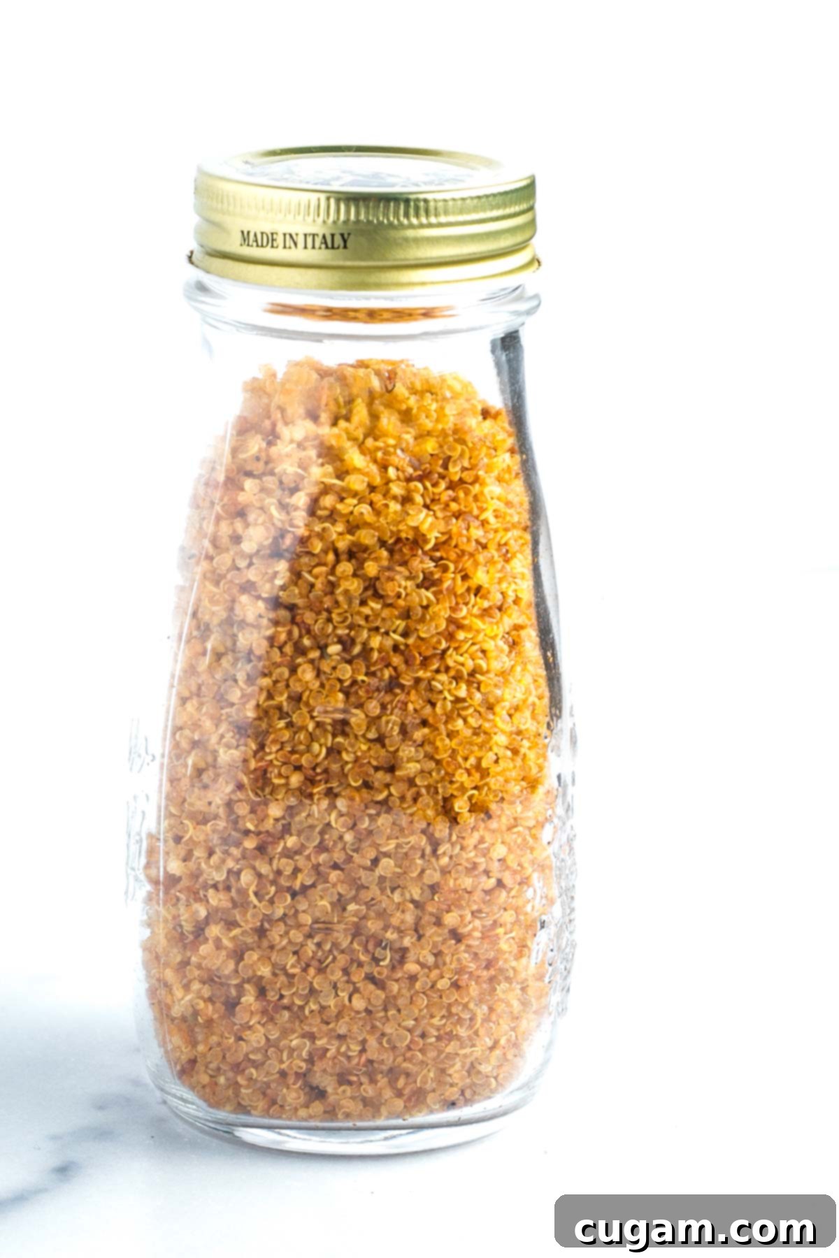 Glass bottle filled with golden, crispy quinoa. 