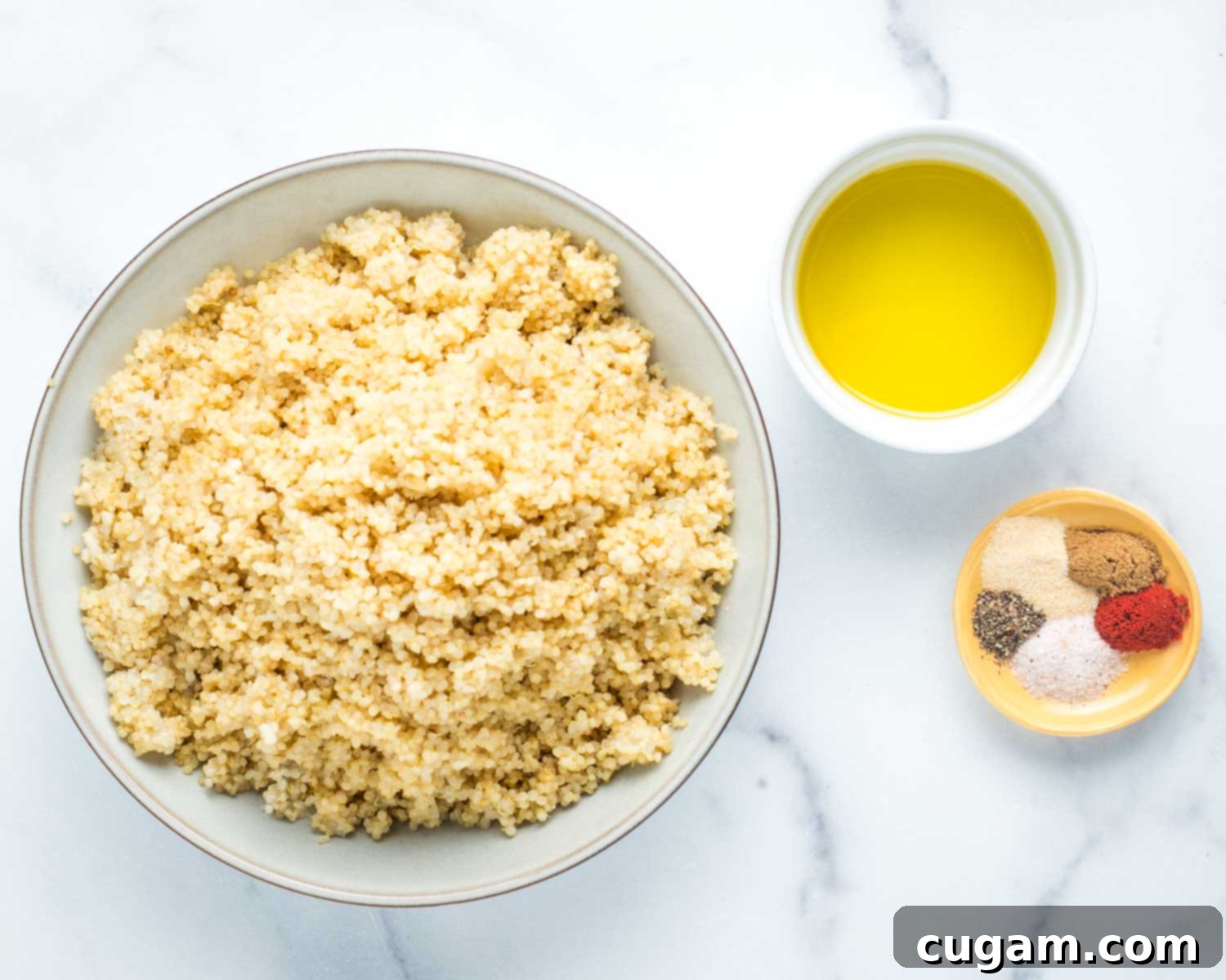 Bowl of cooked quinoa, a dish of olive oil and an assortment of colorful spices.