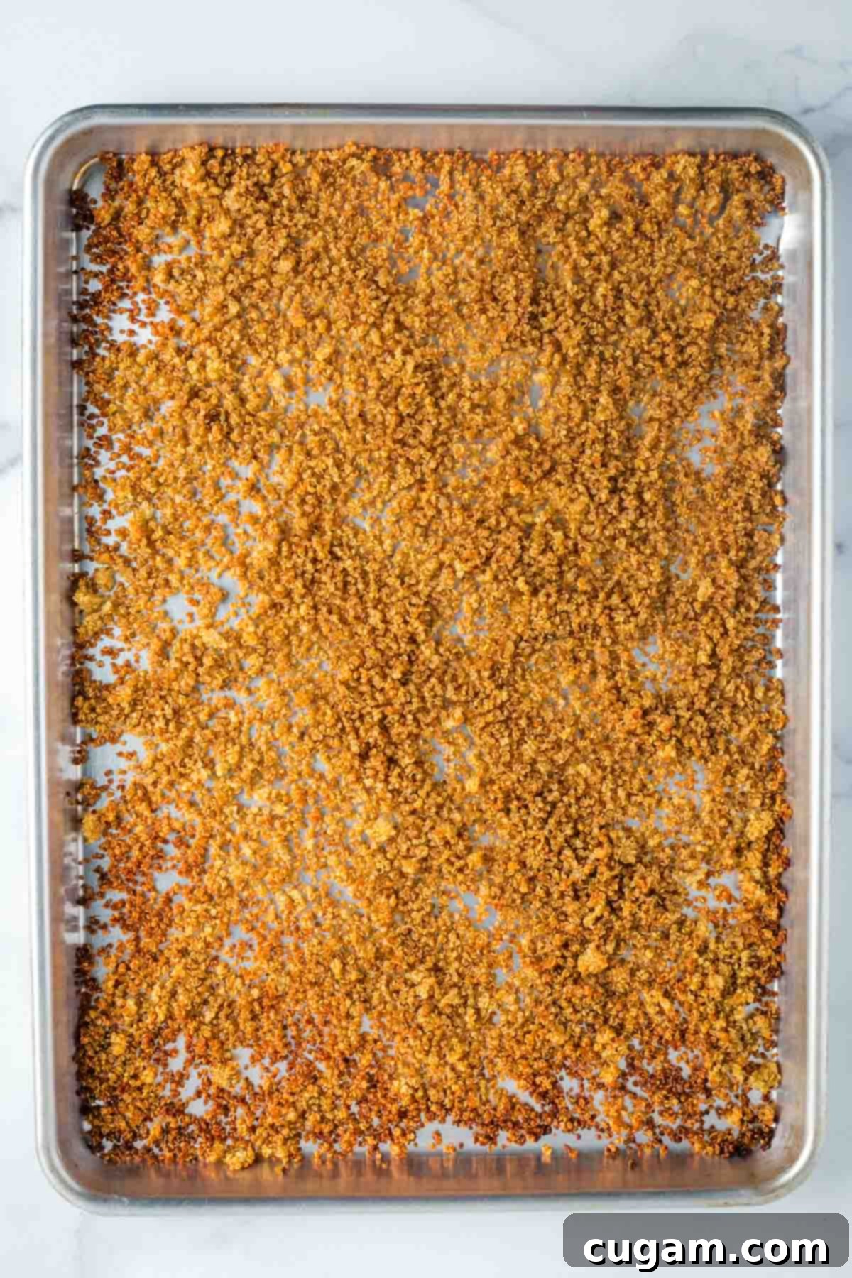 Golden, crispy quinoa spread onto a rimmed baking sheet. 