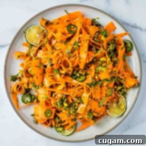 Ribbons of carrots, sprinkled with sliced jalapenos, chopped parsley and pistachios. A vibrant and appetizing close-up of the finished salad.