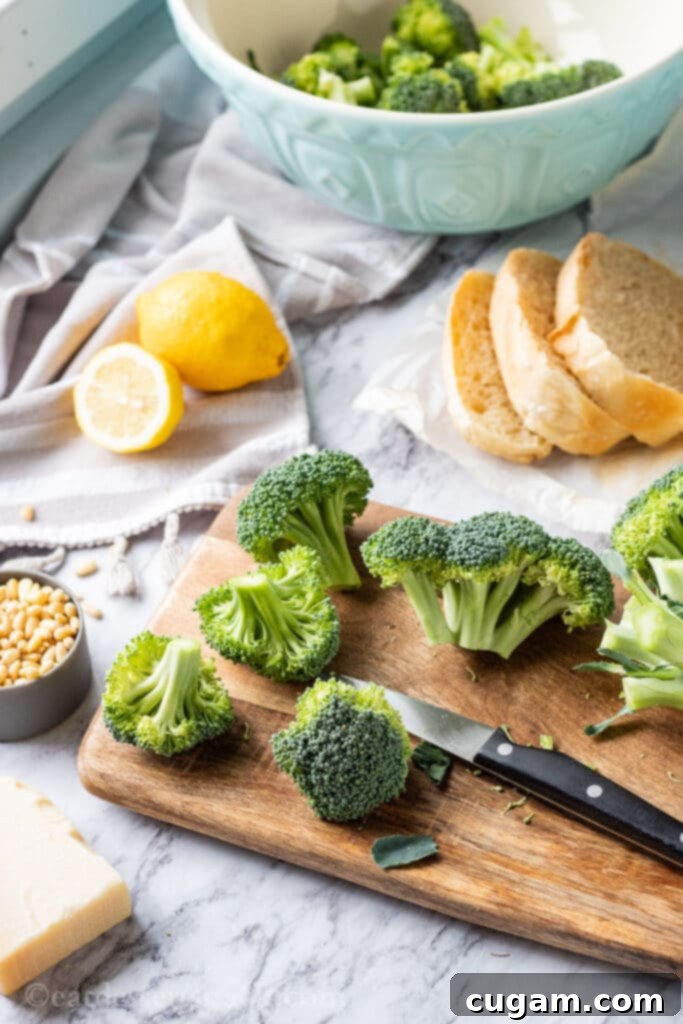 chopped raw broccoli on wood cutting board with lemon and sourdough bread.