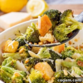 Spoonful of cooked roasted broccoli salad above blue bowl.