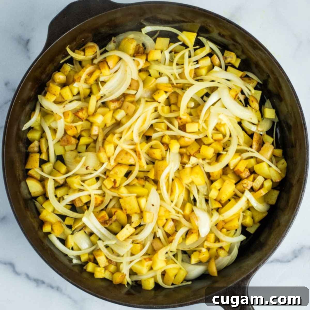 Effortless Vegan Potato and Veggie Skillet 11 Sliced onions are added to the skillet with the partially cooked potatoes, beginning to caramelize.
