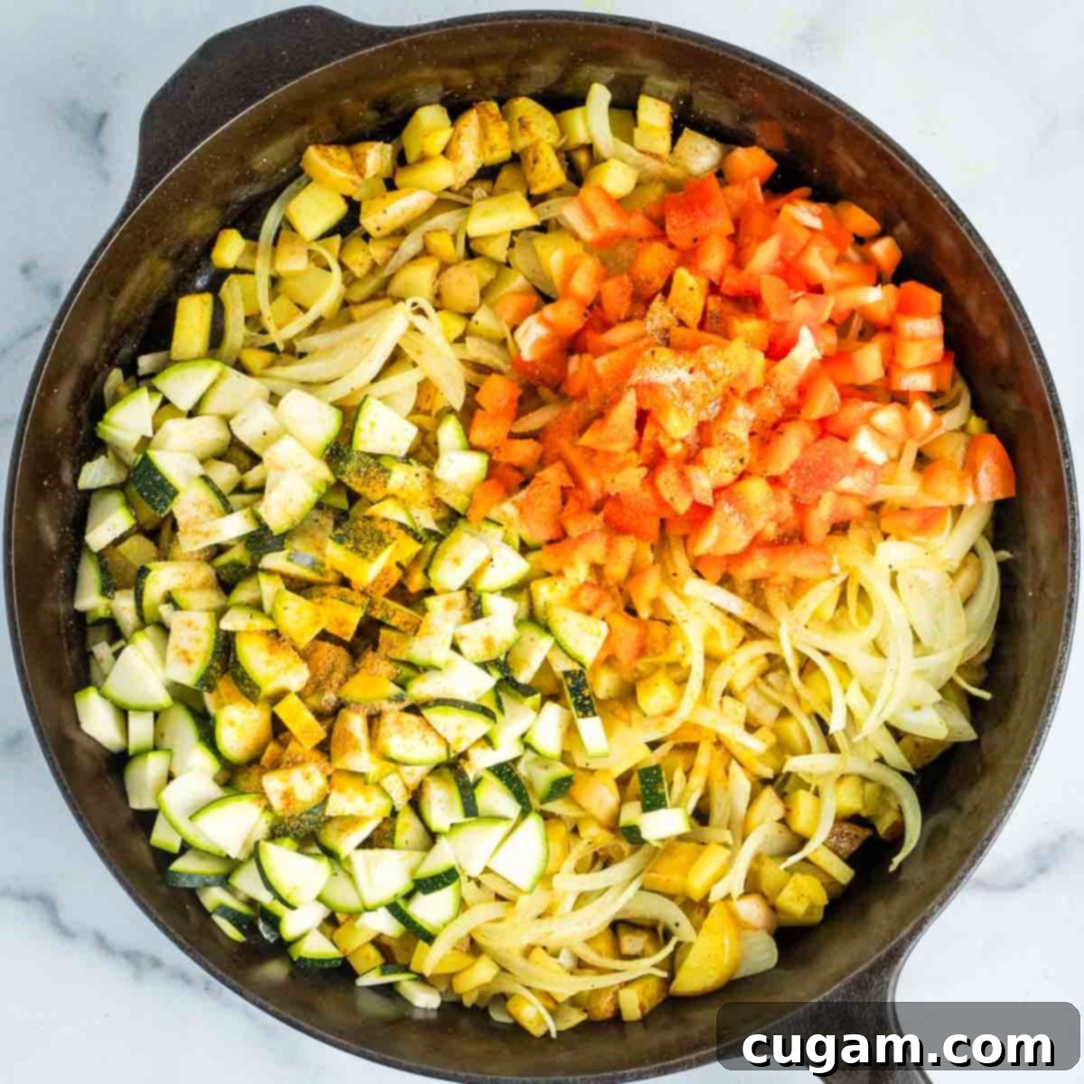Effortless Vegan Potato and Veggie Skillet 12 Chopped zucchini and red bell pepper are added to the potato and onion mixture in the skillet, seasoned with spices.