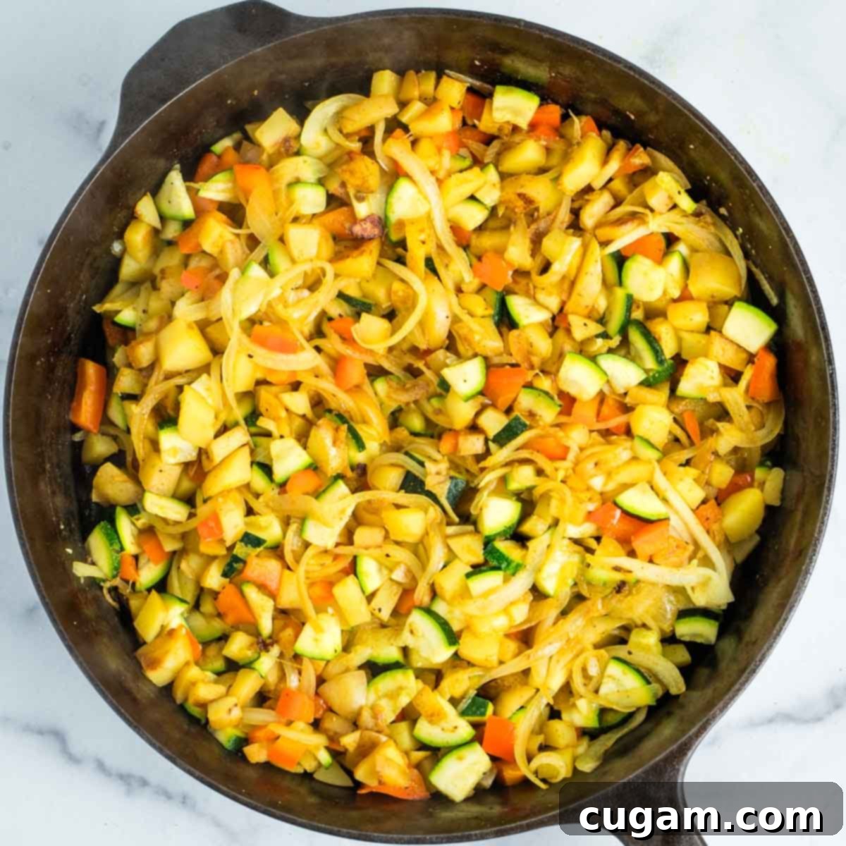 Effortless Vegan Potato and Veggie Skillet 13 The vegetables and spices are thoroughly mixed in the skillet, with a small amount of water added for moisture.