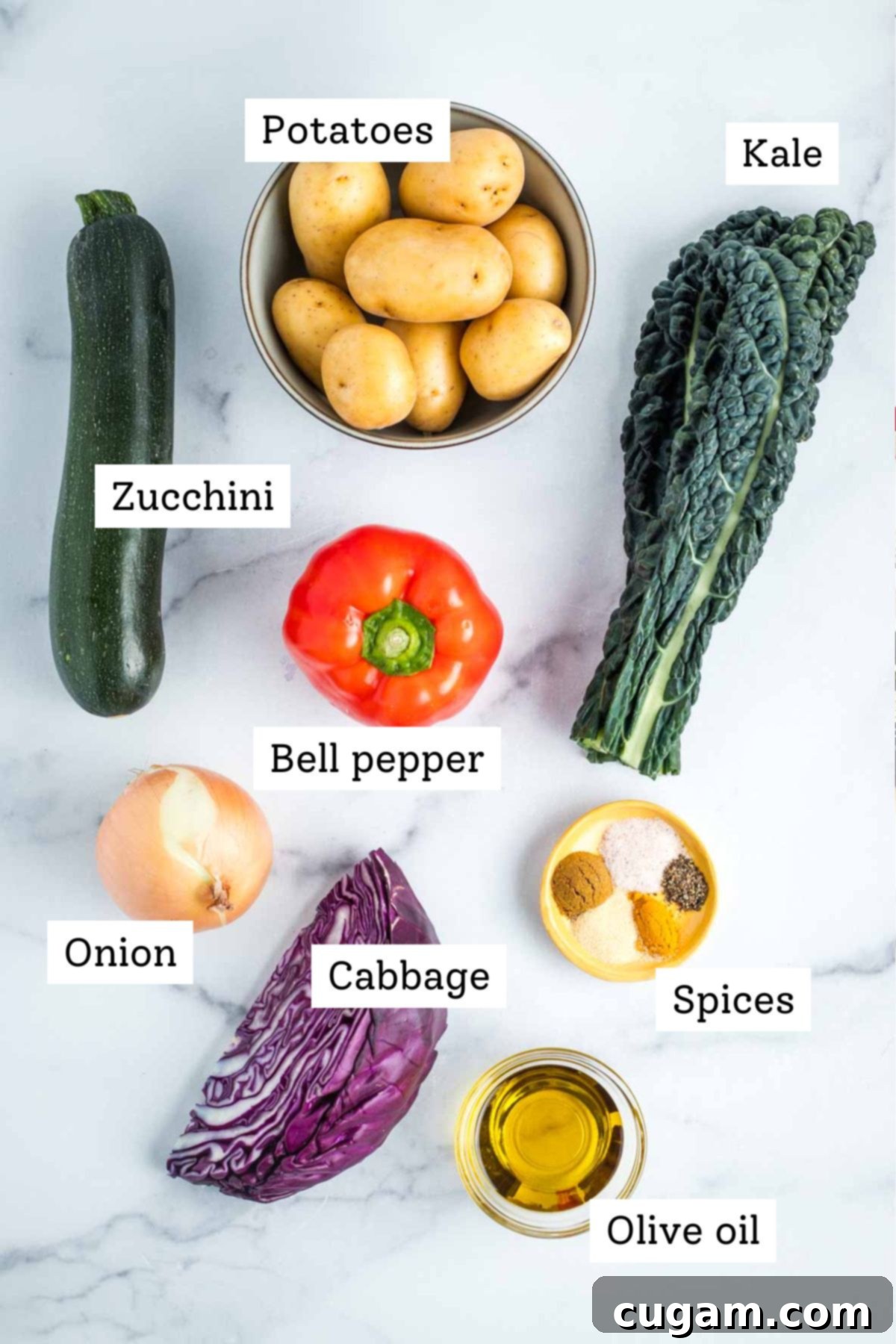 Effortless Vegan Potato and Veggie Skillet 3 A colorful array of labeled ingredients for veggie hash: fresh zucchini, potatoes, kale, red bell pepper, onion, purple cabbage, a selection of spices, and olive oil.