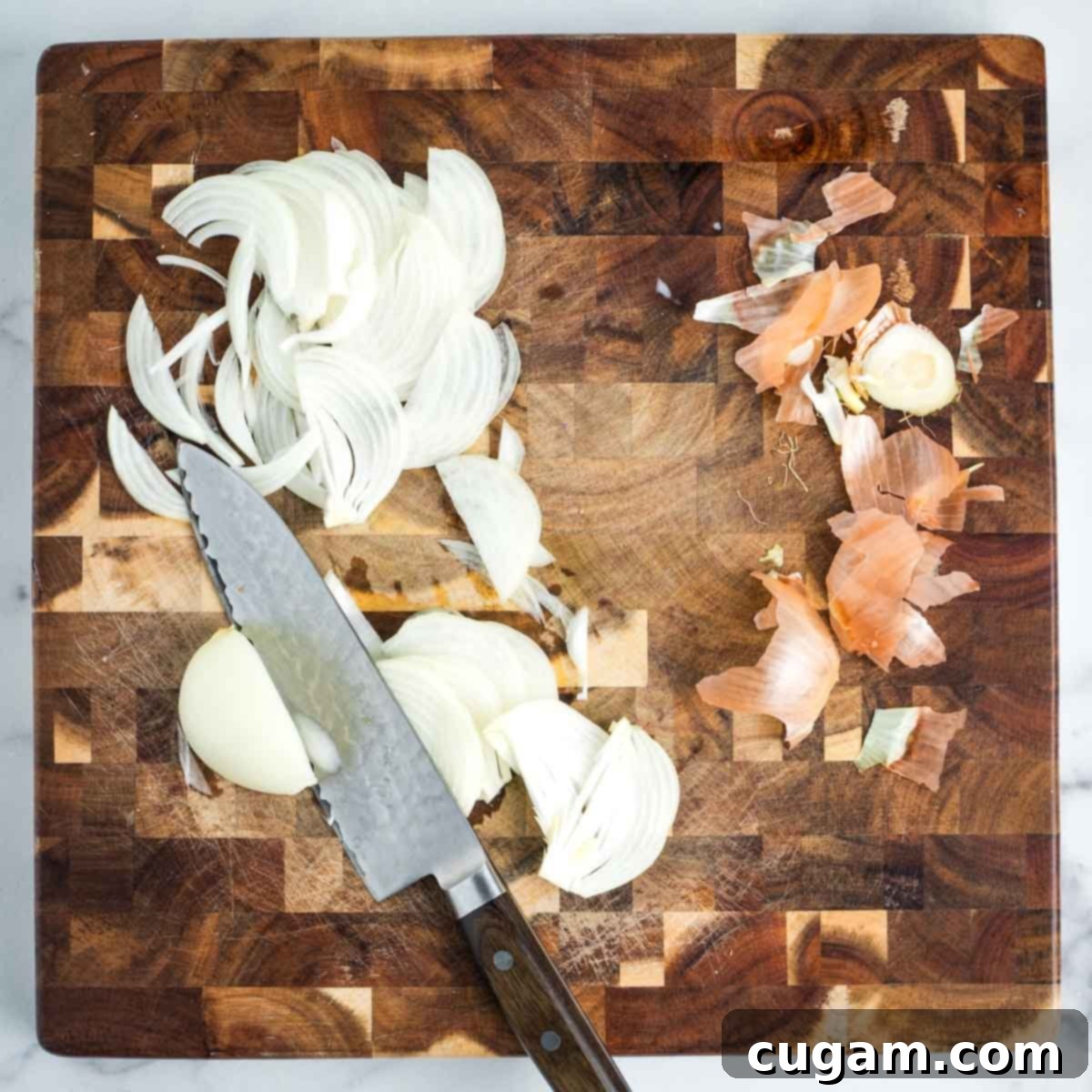Effortless Vegan Potato and Veggie Skillet 4 Thinly slicing an onion on a wooden cutting board, preparing it for the hash.
