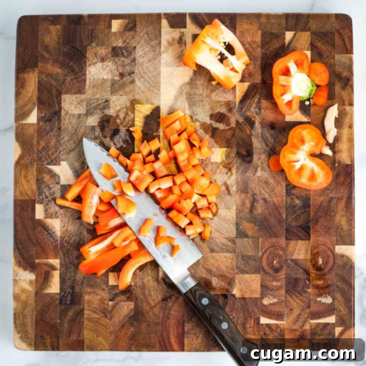 Effortless Vegan Potato and Veggie Skillet 6 Demonstrating how to dice a red bell pepper into small, even cubes on a wooden cutting board.