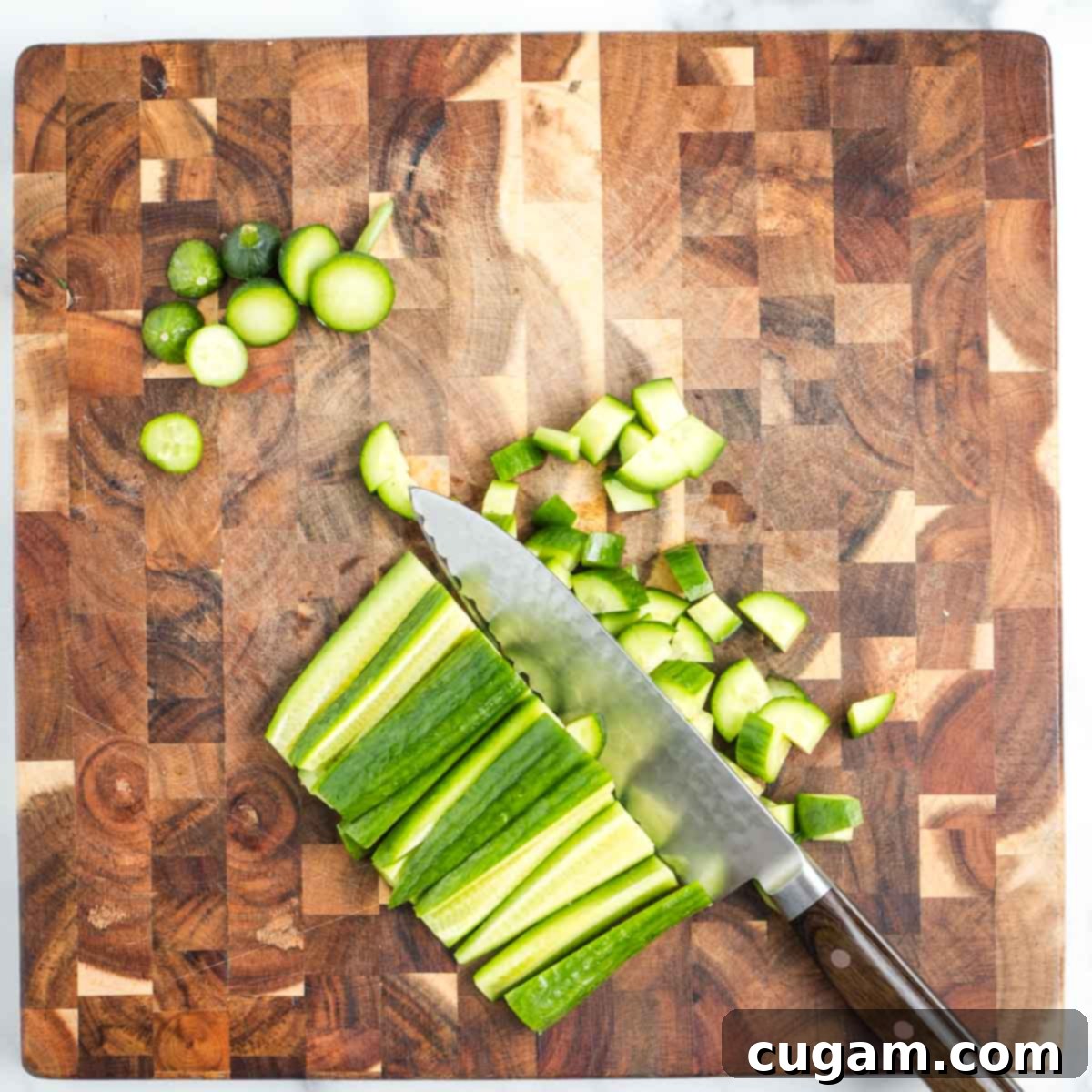 Cutting across cucumber strips to create small dice.