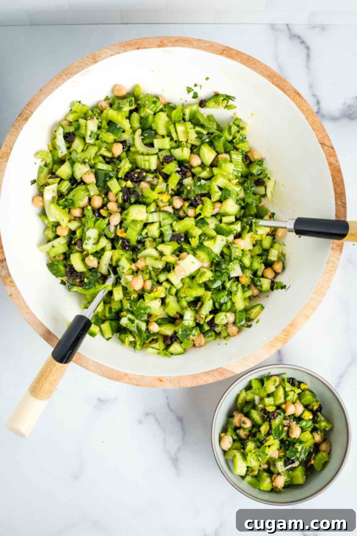 A large white bowl with wood trim filled with the fully mixed chopped celery salad.