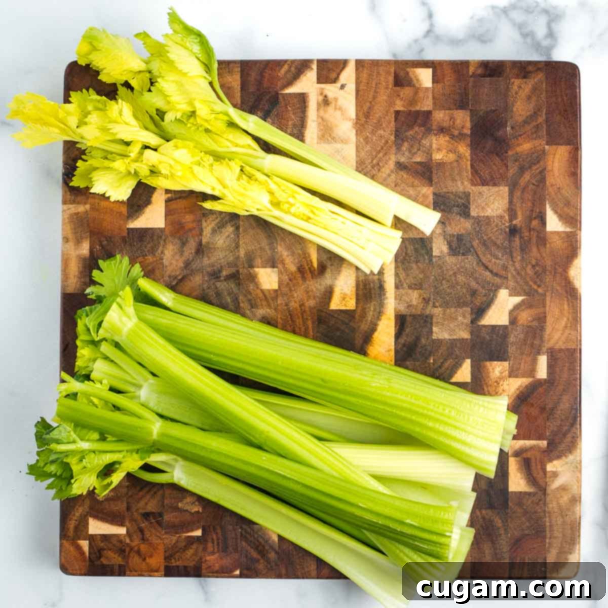 Two piles of celery stalks. One darker and firmer, the other light colored with leaves.