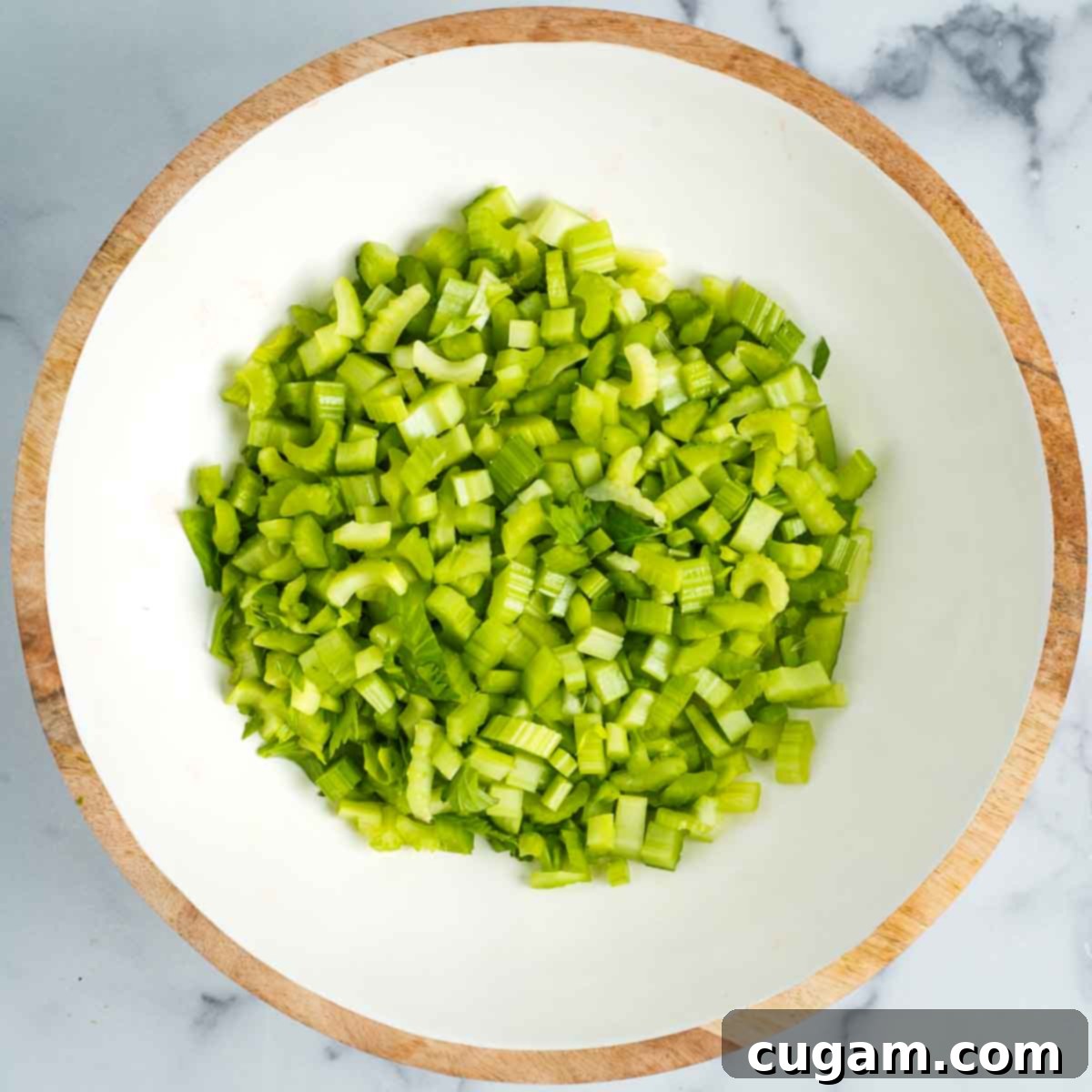 Diced celery in a white bowl with wood trim.