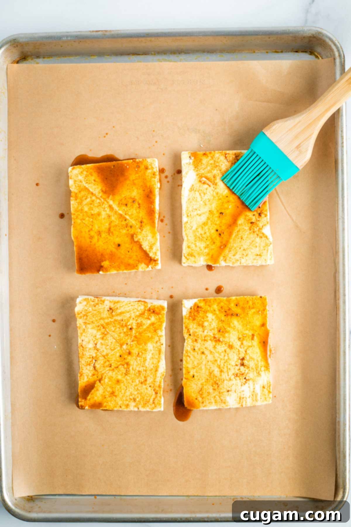 Brushing marinade onto tofu steaks on a sheet pan.