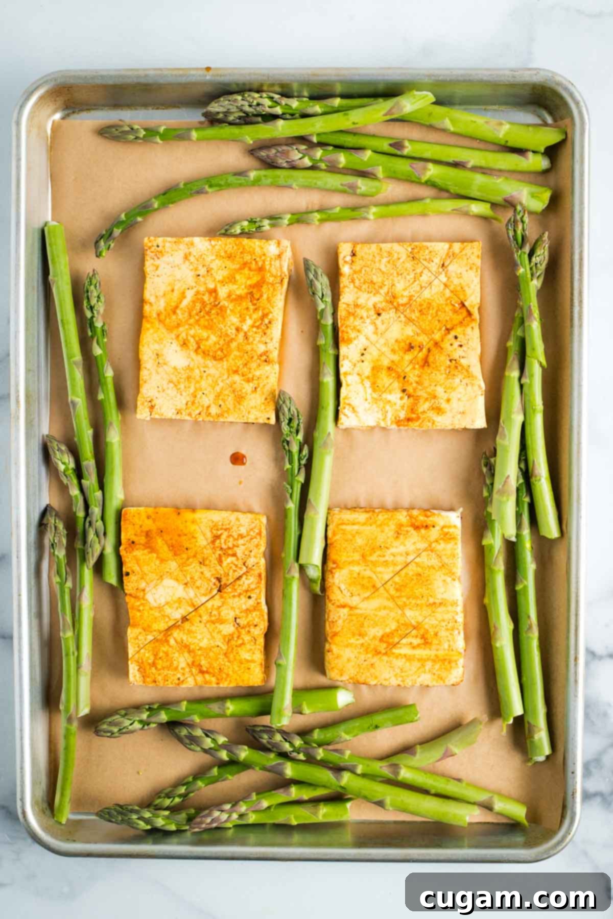 Marinated tofu steaks on a sheet pan surrounded by asparagus.