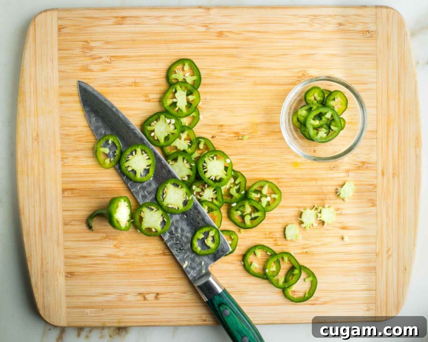 Slicing thin pieces of jalapeno, and pulling out the membranes and seeds from the center of the slices.