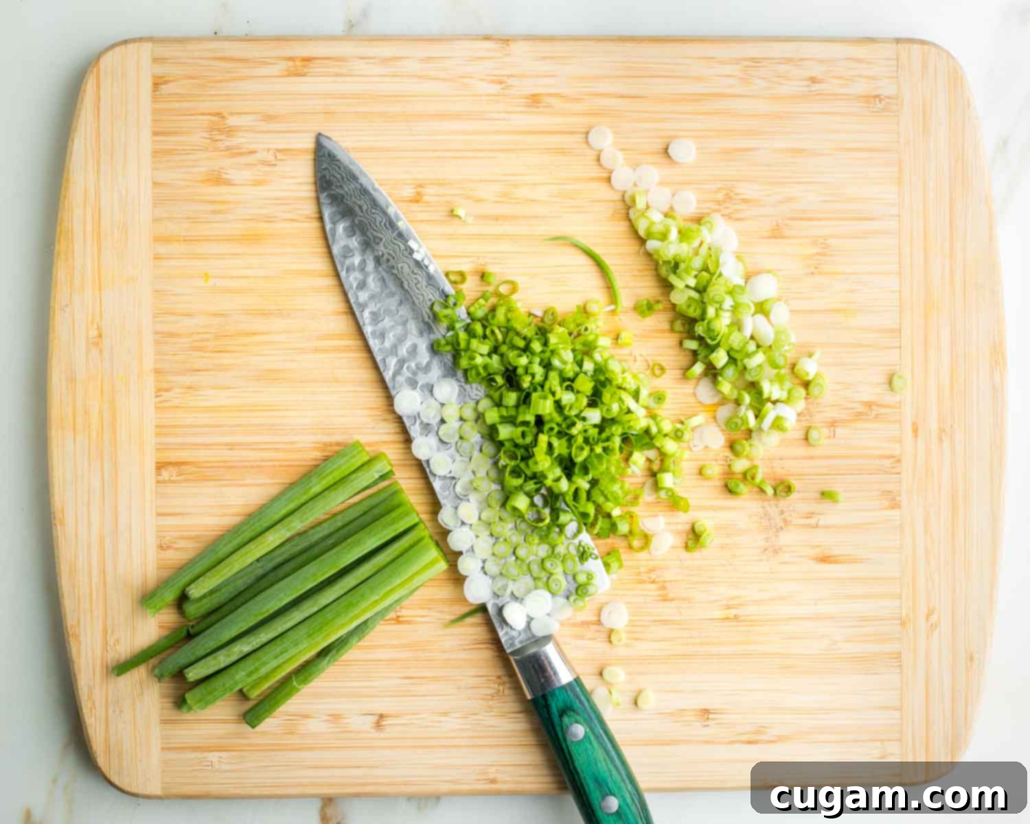 Thinly slicing white and green parts of scallions.