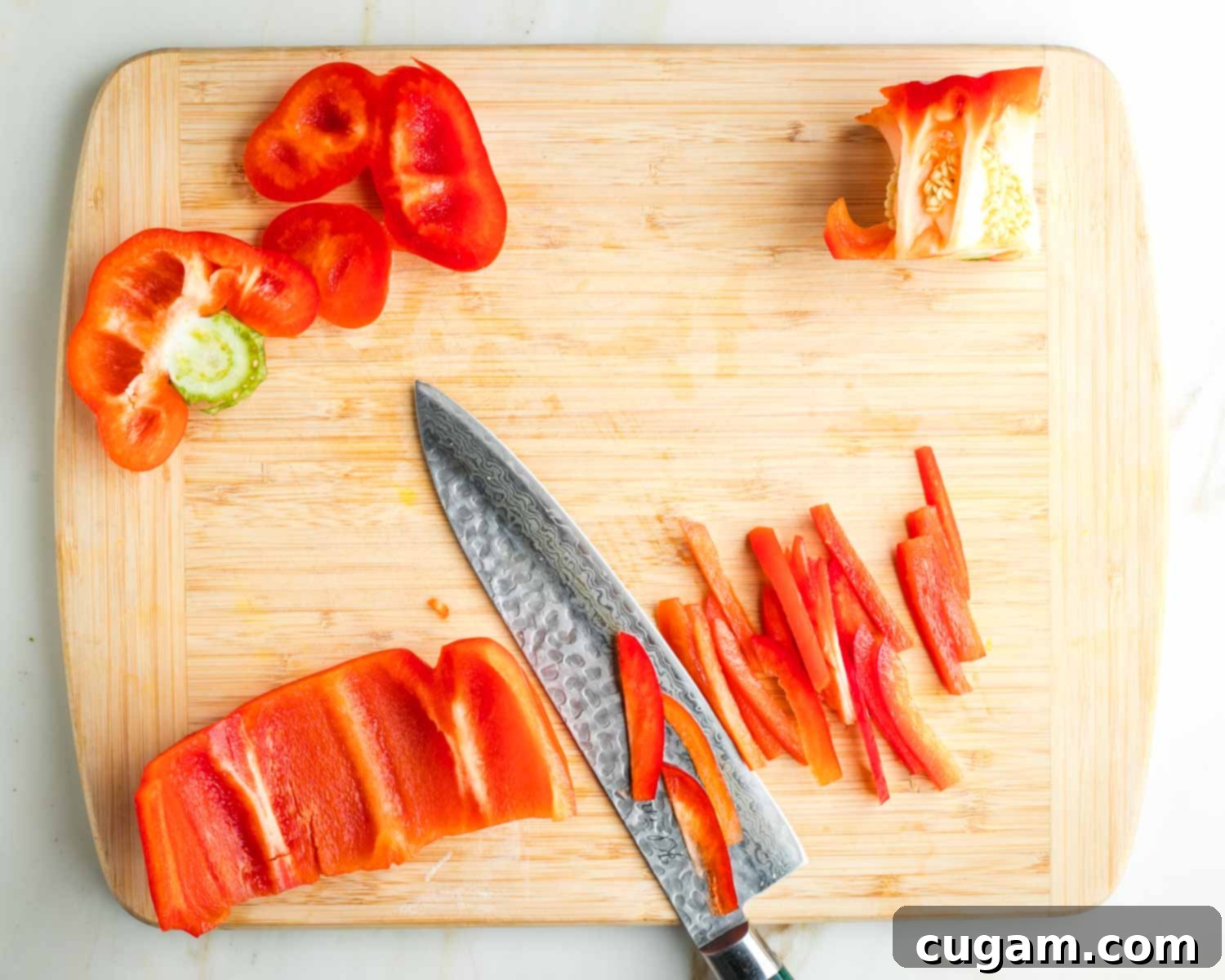 Showing how to thinly slice red bell pepper with top and center trimmed off.