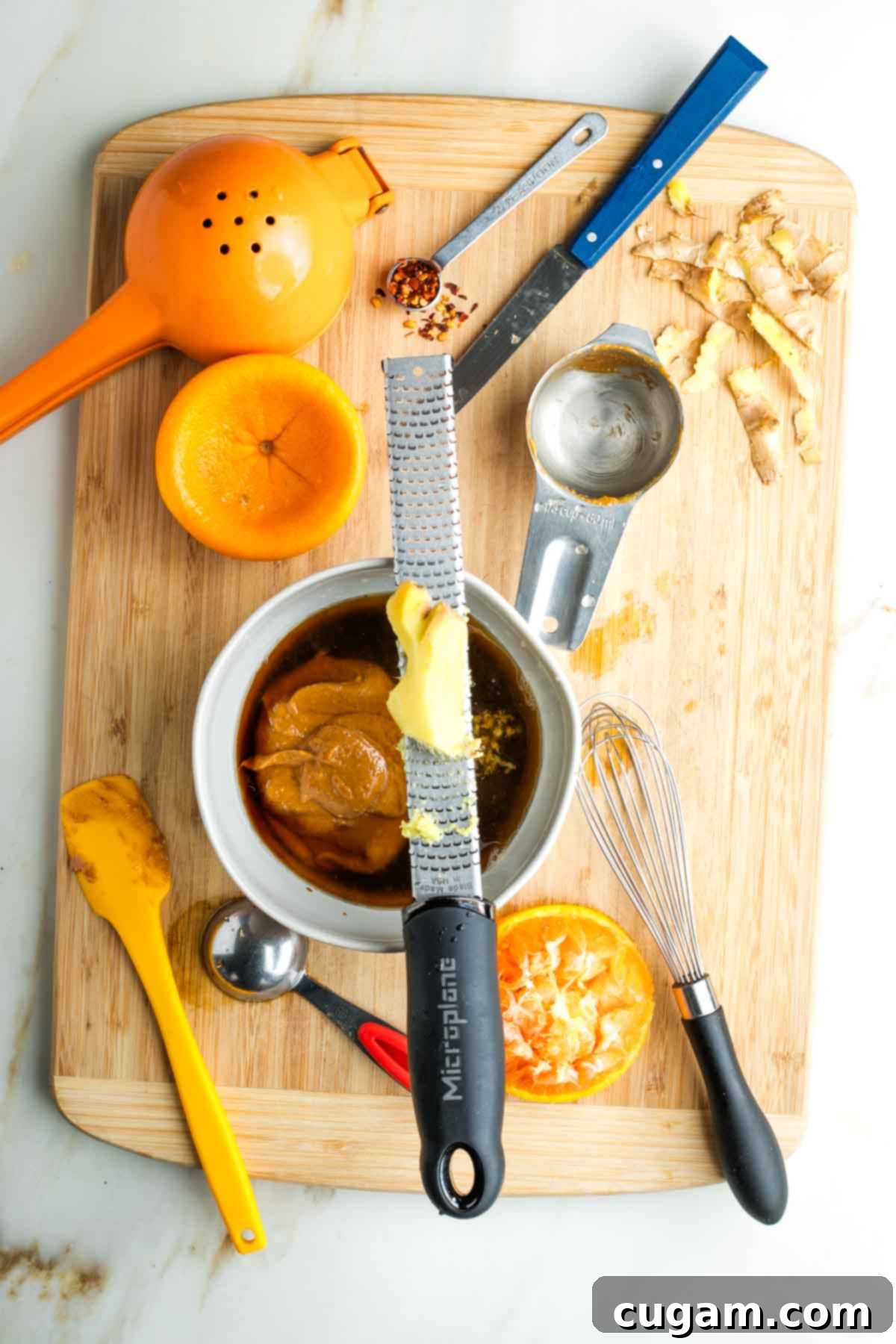 Grating fresh ginger over a bowl with brown liquid and a dollop of peanut butter.