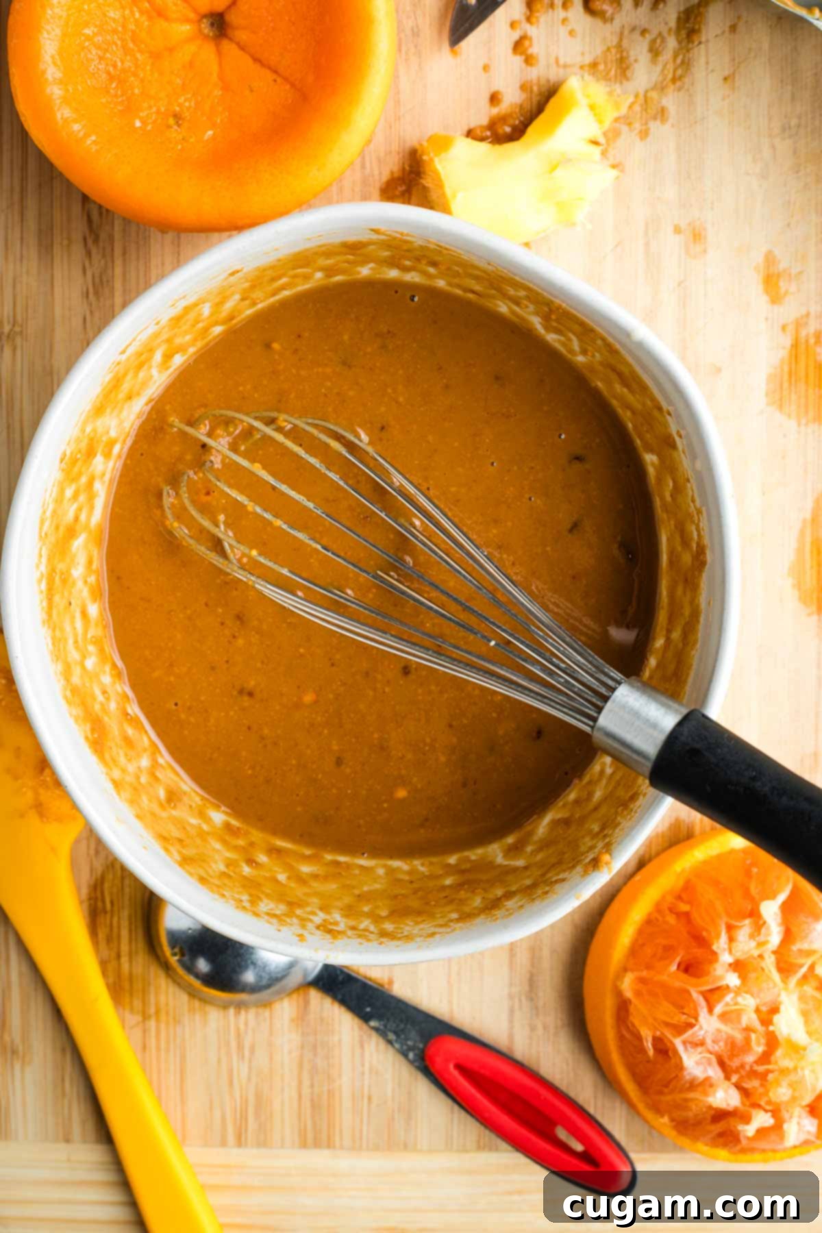 Whisking peanut dressing together, squeezing oranges into the bowl.