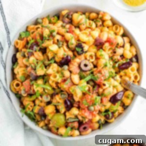 Pasta, white beans, olives and capers with tomatoes and fresh parsley, presented in a bowl.