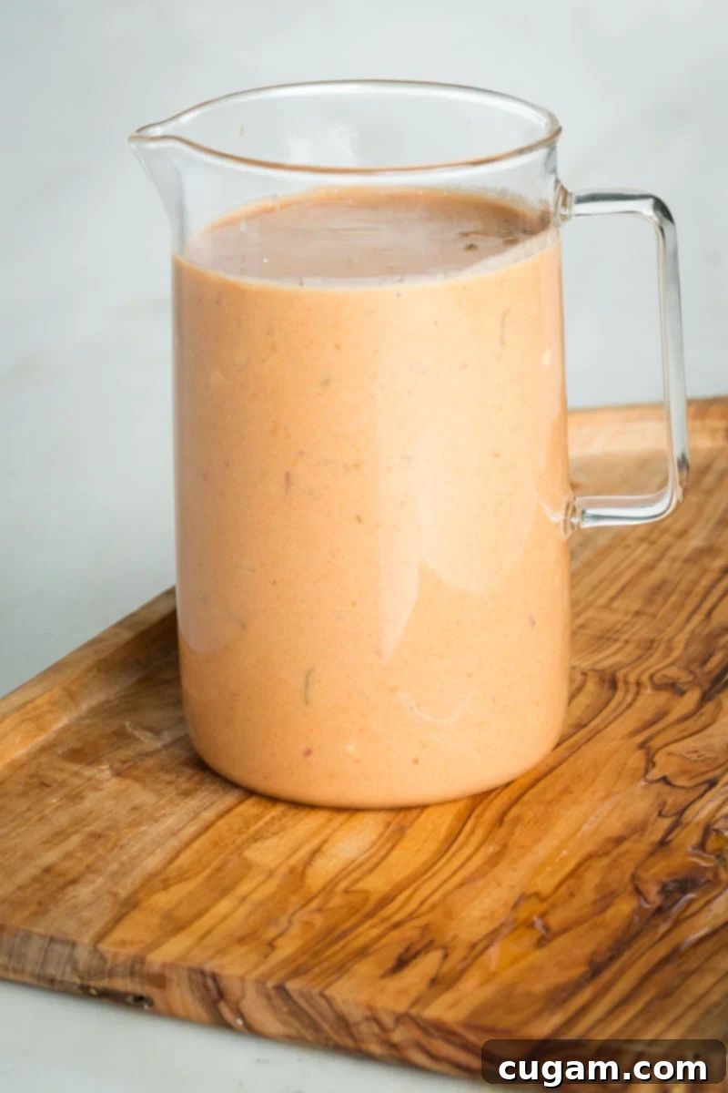 Small glass pitcher with creamy orange dressing. 