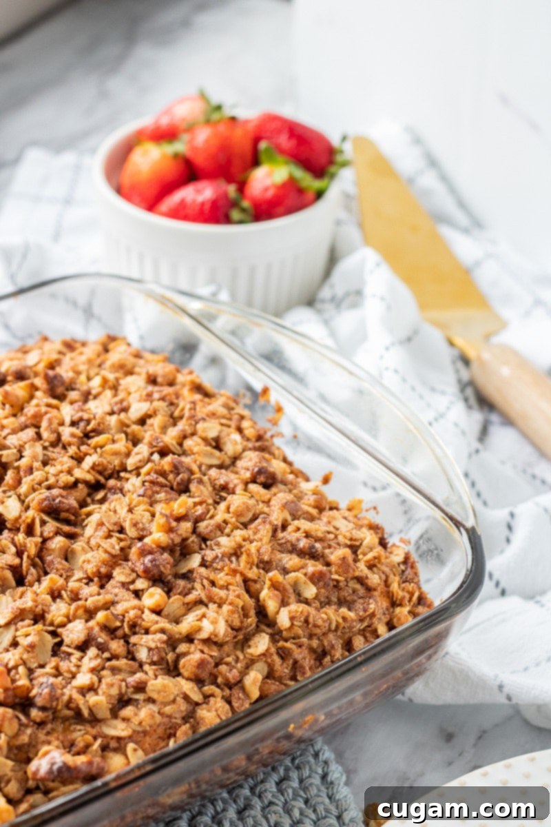 A perfectly baked classic coffee cake, fresh from the oven, served unsliced with fresh strawberries and a spatula. Ideal for a family breakfast.