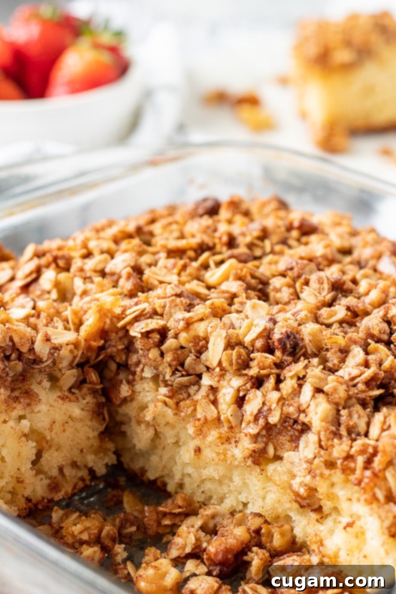 A baked classic coffee cake in a clear glass pan, garnished with fresh strawberries, ready to be served for a delightful breakfast or brunch. Perfect for make-ahead convenience.