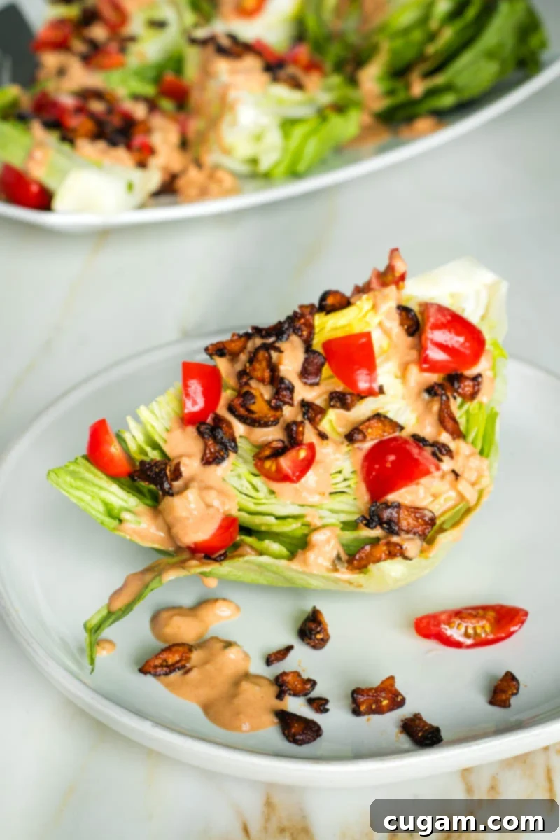 A wedge of iceberg lettuce drizzled with Russian dressing plus chopped tomatoes and shiitake bacon crumbles. A perfect, vibrant vegan wedge salad.