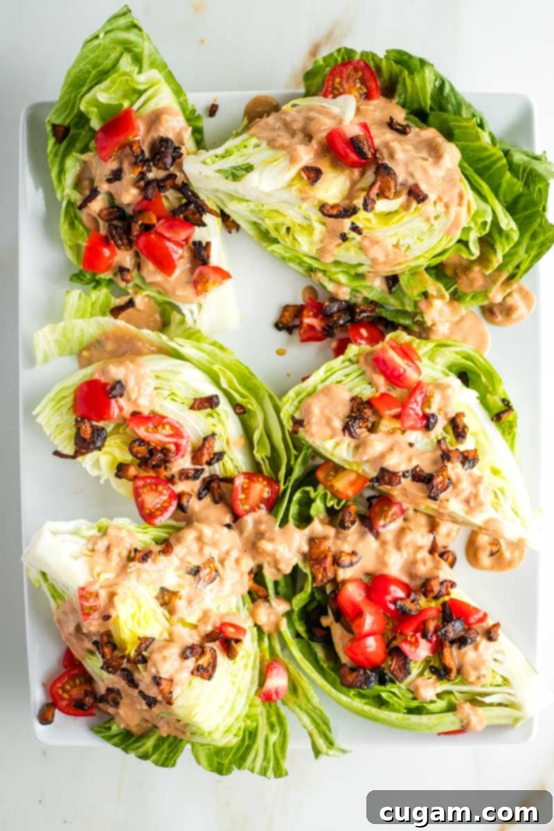 Wedges of iceberg lettuce on a platter with Russian dressing, shiitake bacon crumbles and chopped tomatoes. 