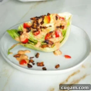 Wedge of iceberg lettuce with russian dressing, vegan bacon crumbles and diced tomatoes.