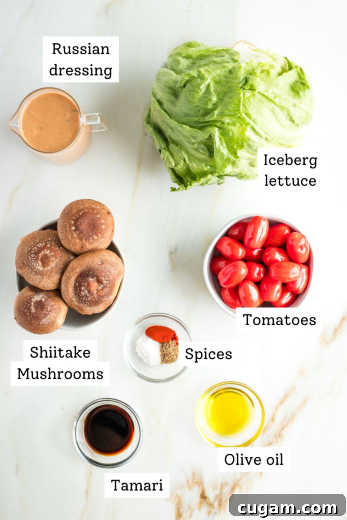 Assortment of fresh ingredients for vegan wedge salad including iceberg lettuce, tomatoes, and shiitake mushrooms.