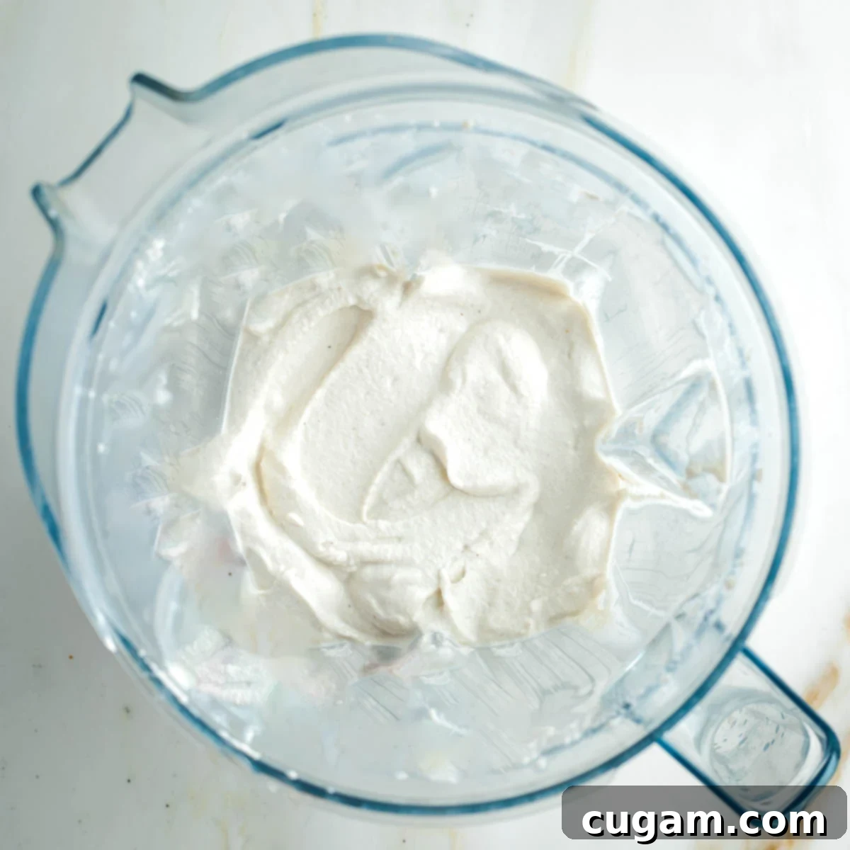 The blender pitcher contains a thick, pristine white cashew cream, perfectly smooth and ready to be combined with other ingredients for the dip.