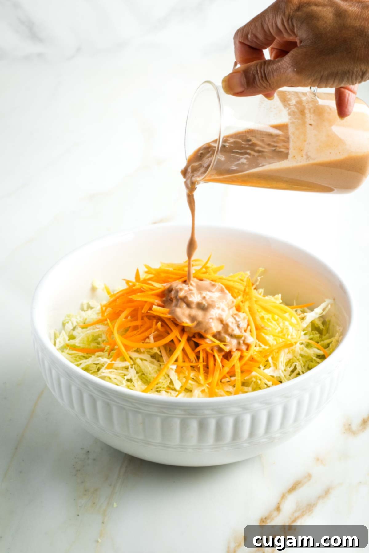 Zesty Russian Slaw 12 Pouring Russian dressing onto a bowl of shredded cabbage and carrots.