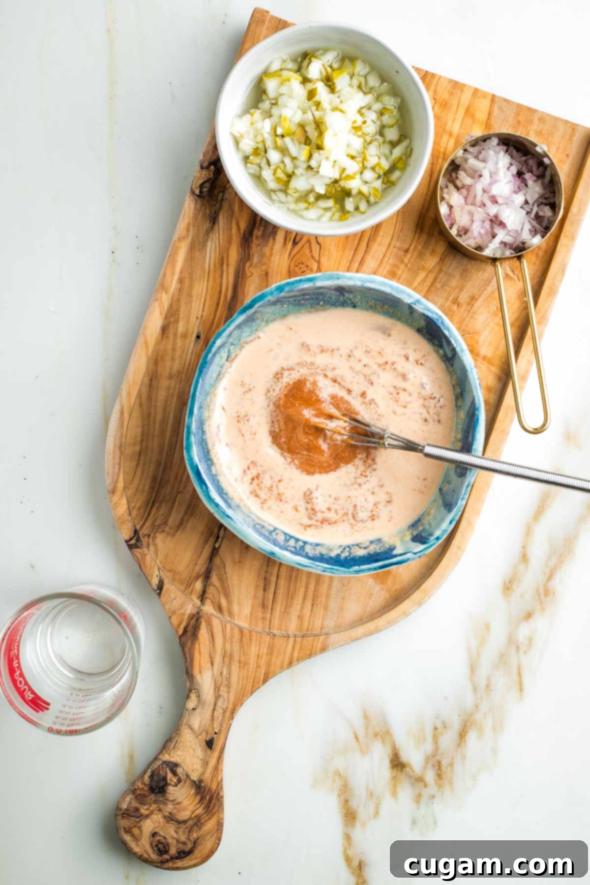 Zesty Russian Slaw 10 Whisking water into a pasty red sauce in a small bowl.