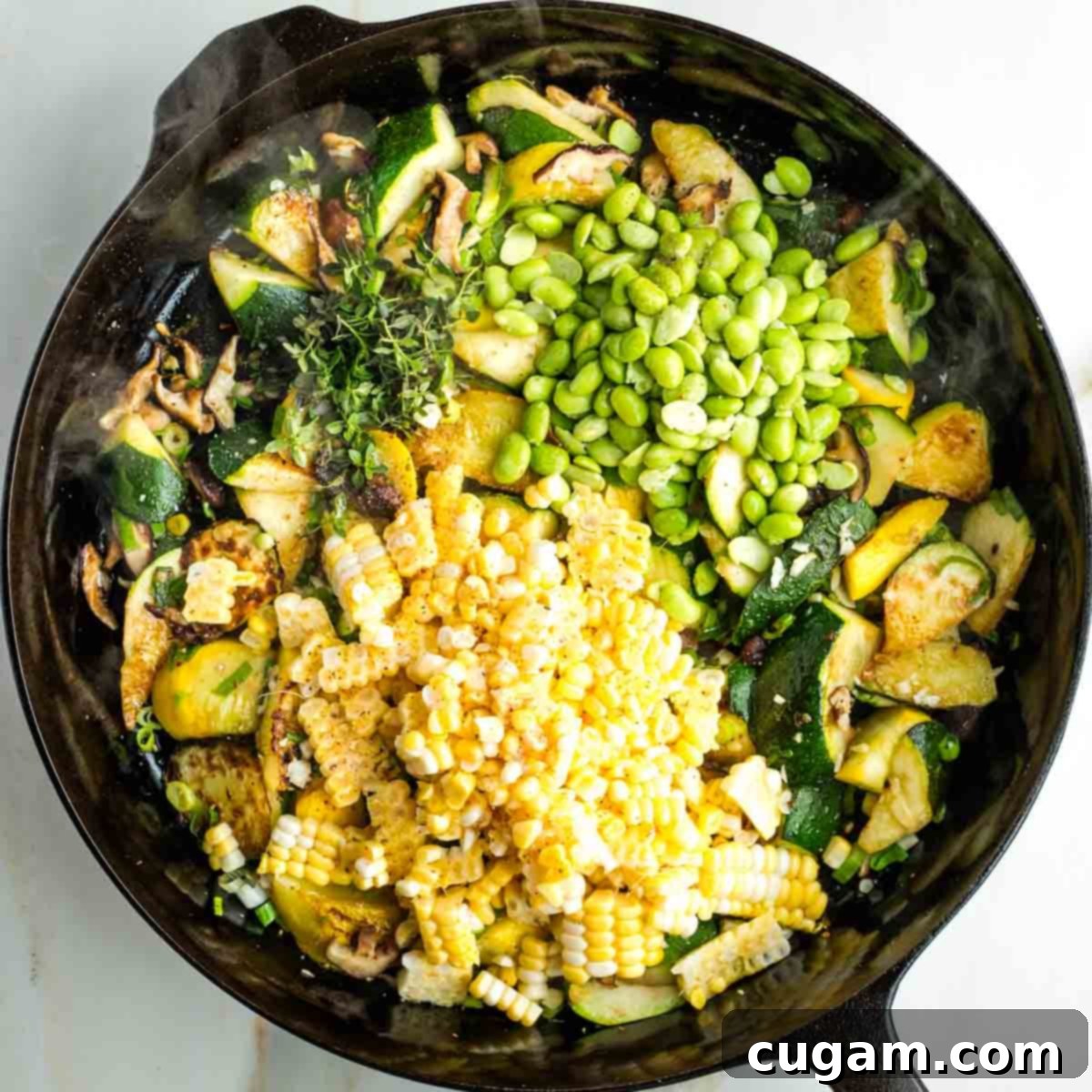 Corn kernels, edamame beans, and fresh thyme on top of charred zucchini and mushrooms in a skillet.