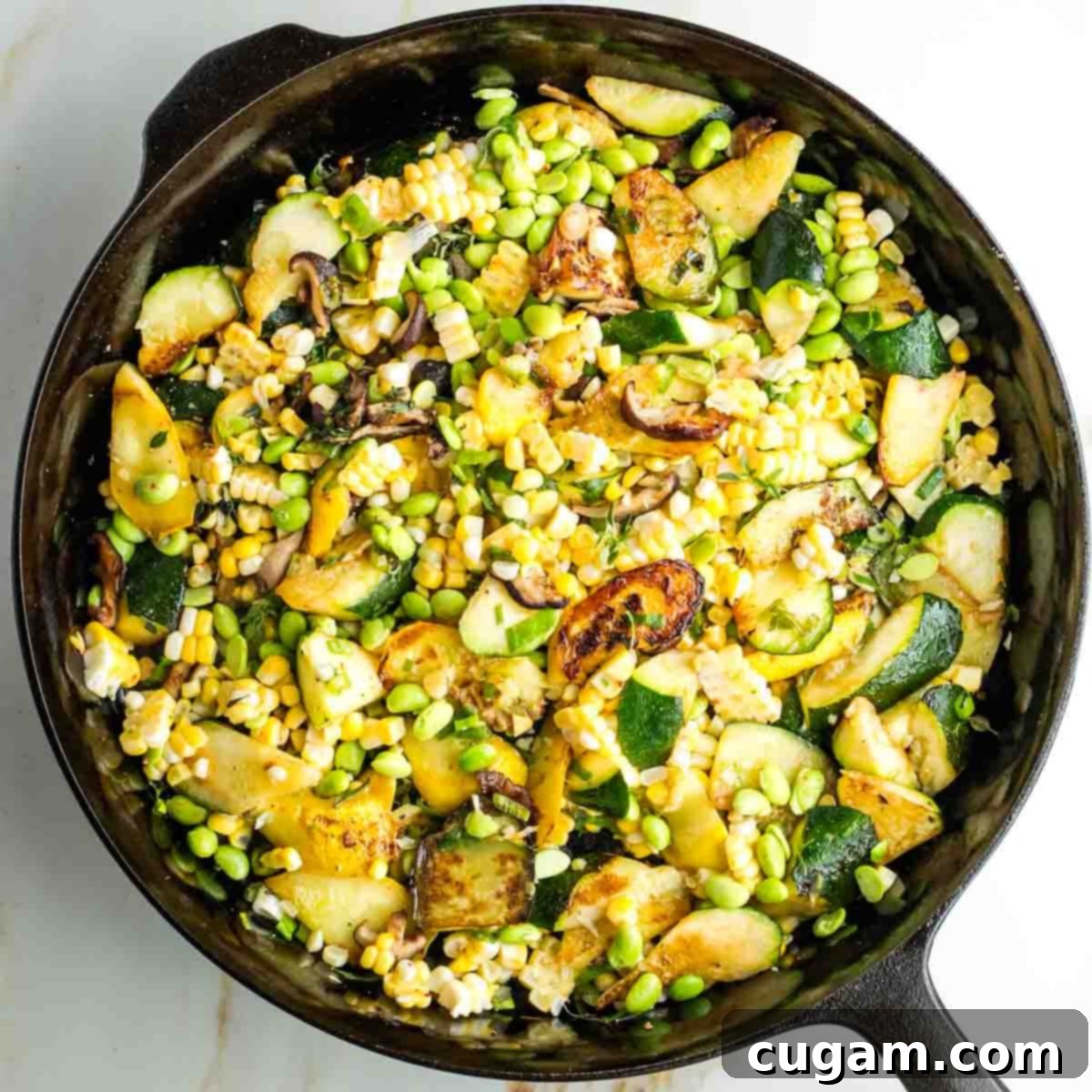 Zucchini, corn, edamame, mushrooms, and scallions cooking together in a cast iron skillet, nearing completion.
