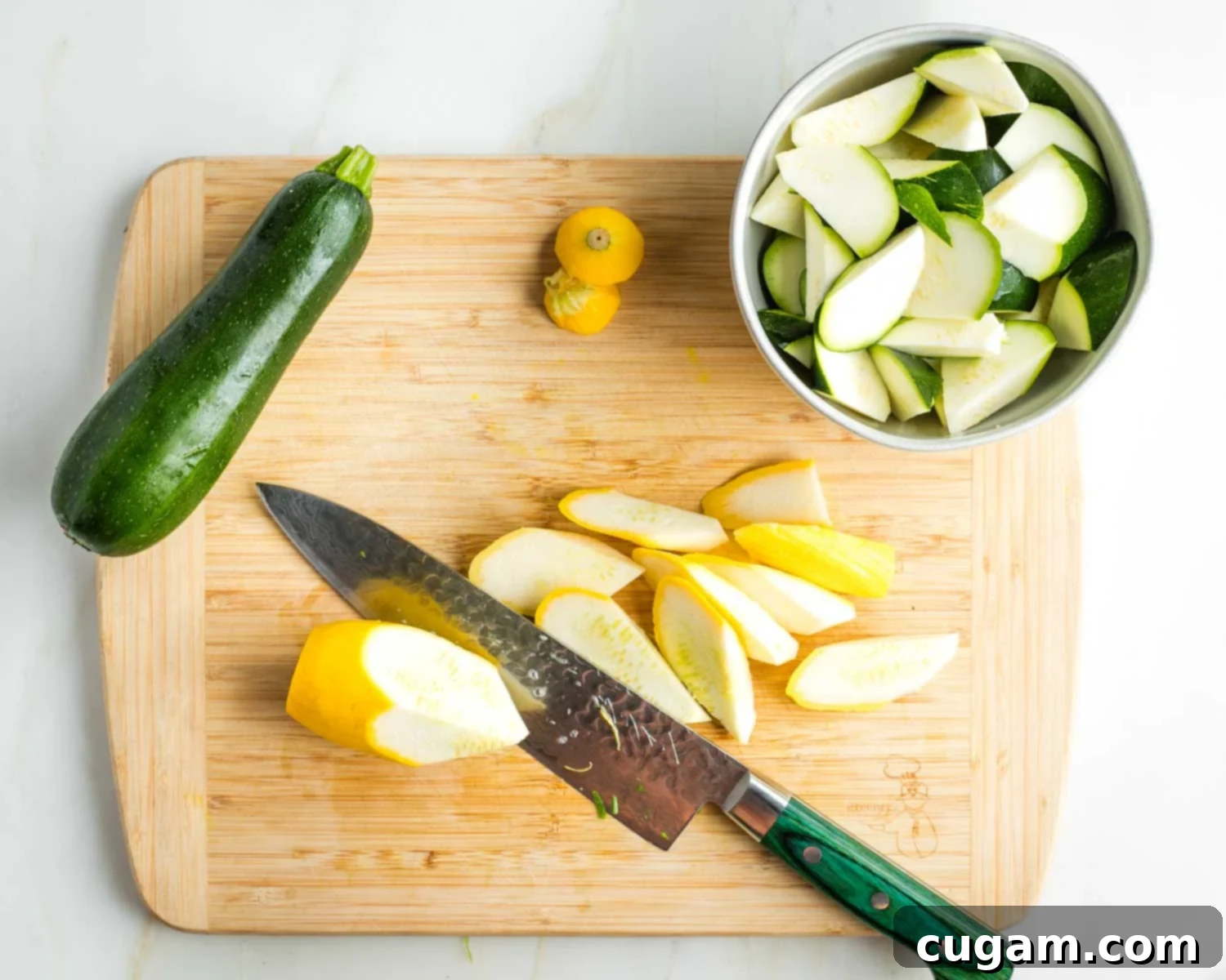 Zucchini and summer squash cut into diagonal cubes on a cutting board.