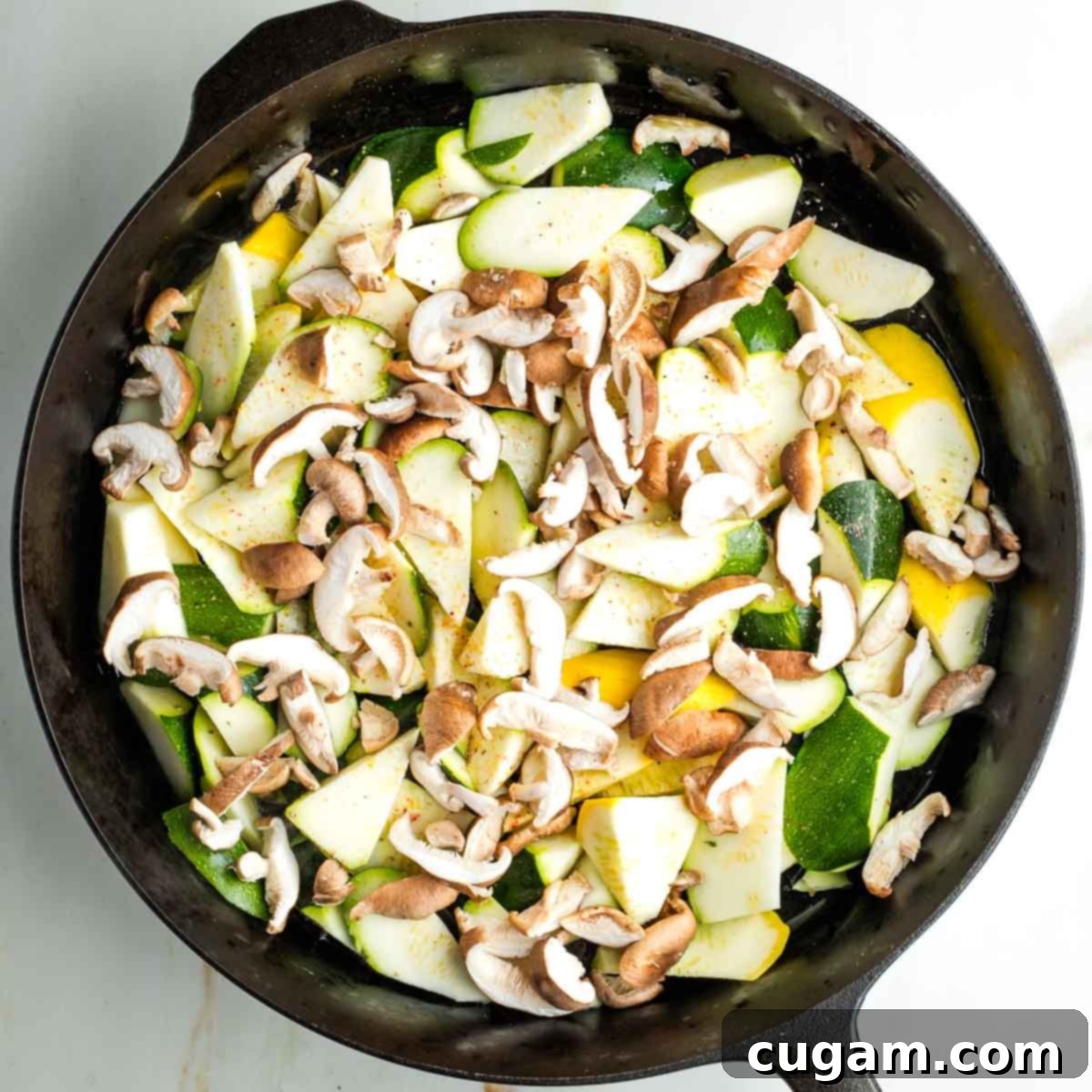 Raw zucchini and yellow summer squash in a hot skillet with sliced shiitake mushrooms, sprinkled with salt and pepper, about to be charred.