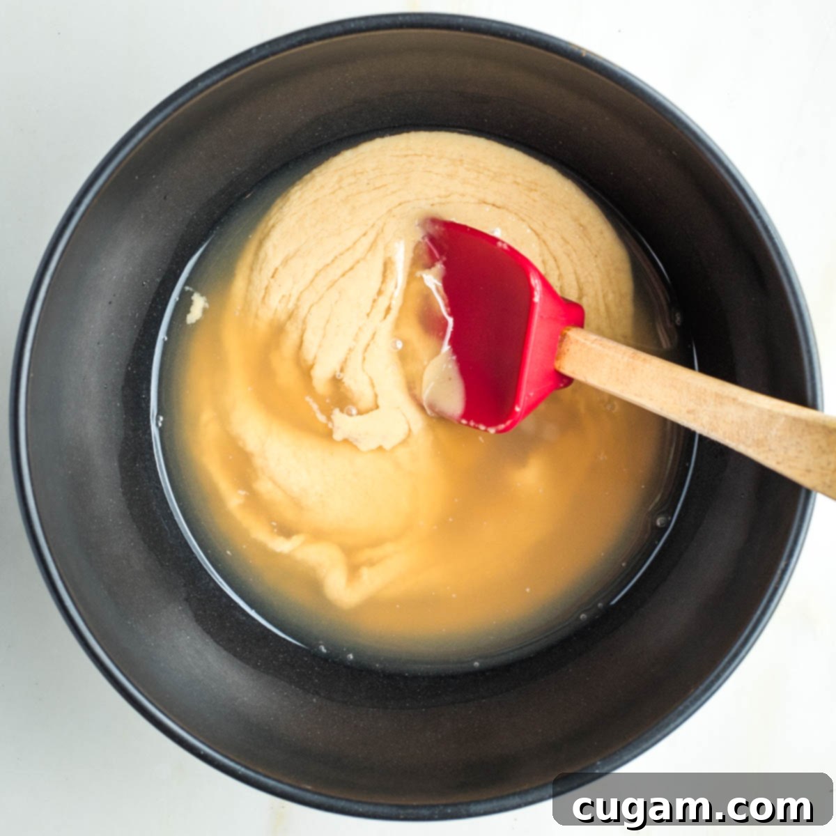 Stirring water and lemon juice into tahini.