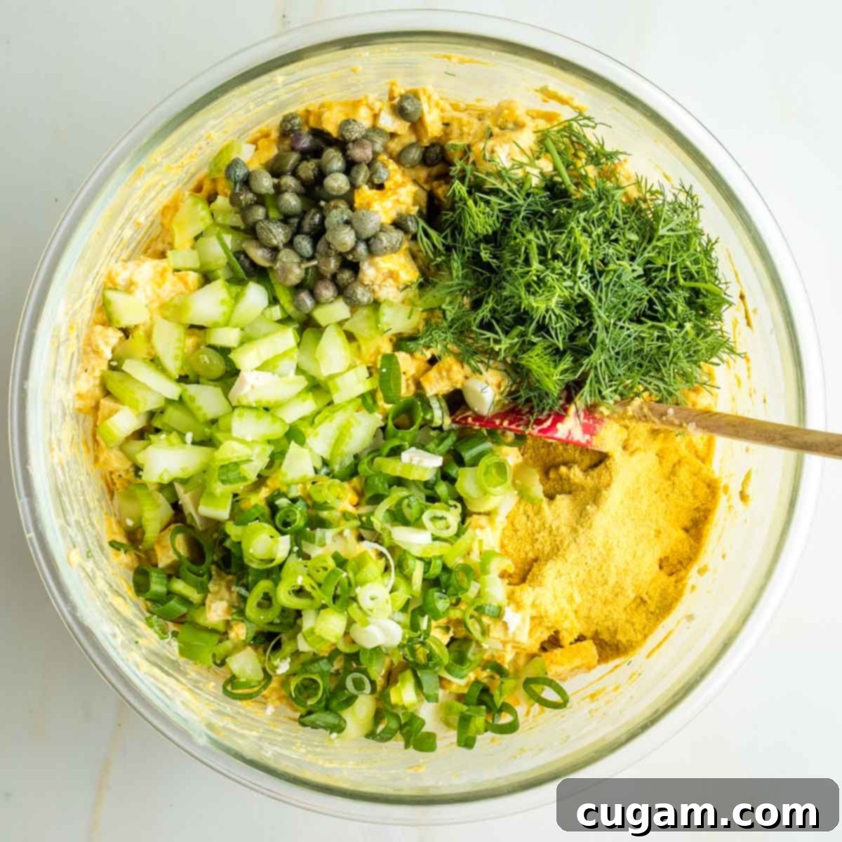 Diced celery, minced dill, sliced scallions, capers, spices and nutritional yeast over a creamy yellow sauced tofu pieces. 