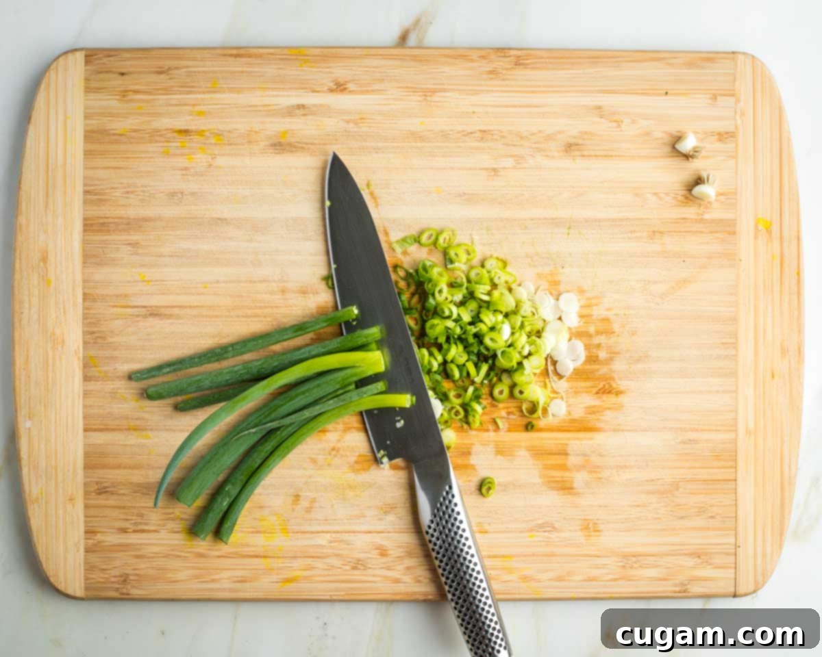 Thinly slicing white and green parts of scallions.