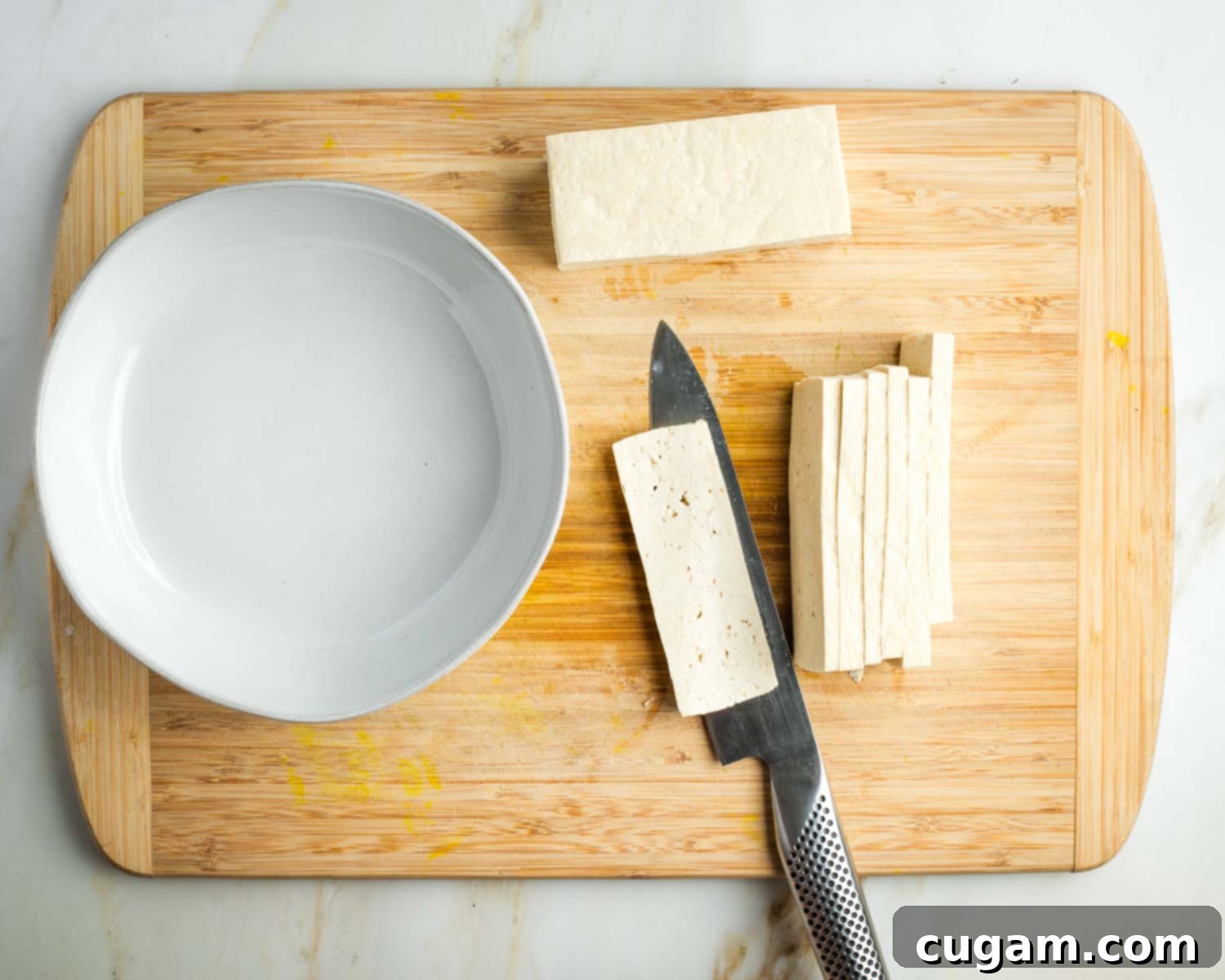 Cutting half a block of tofu into thin slices.