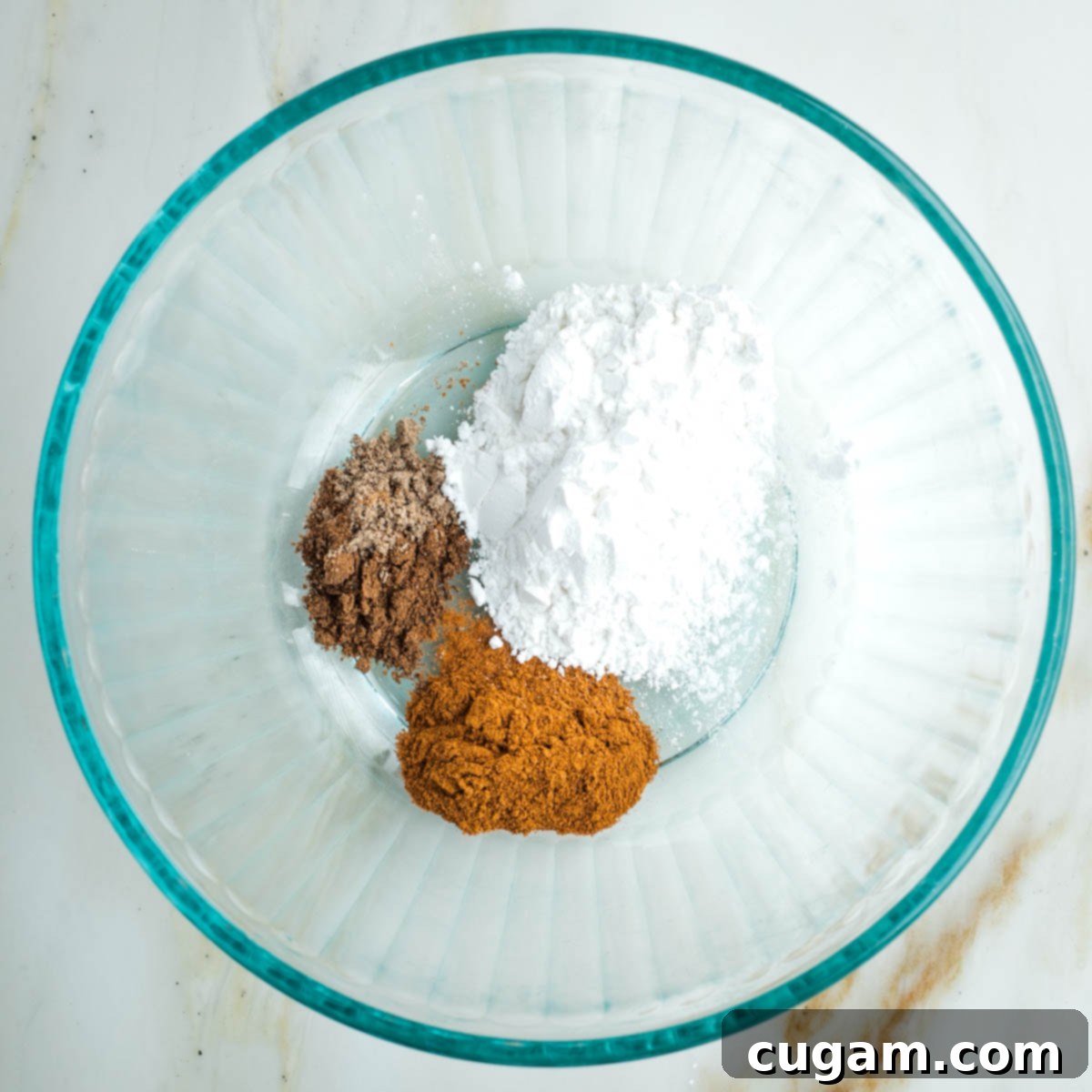 Glass bowl with white arrowroot powder and various brown spices.