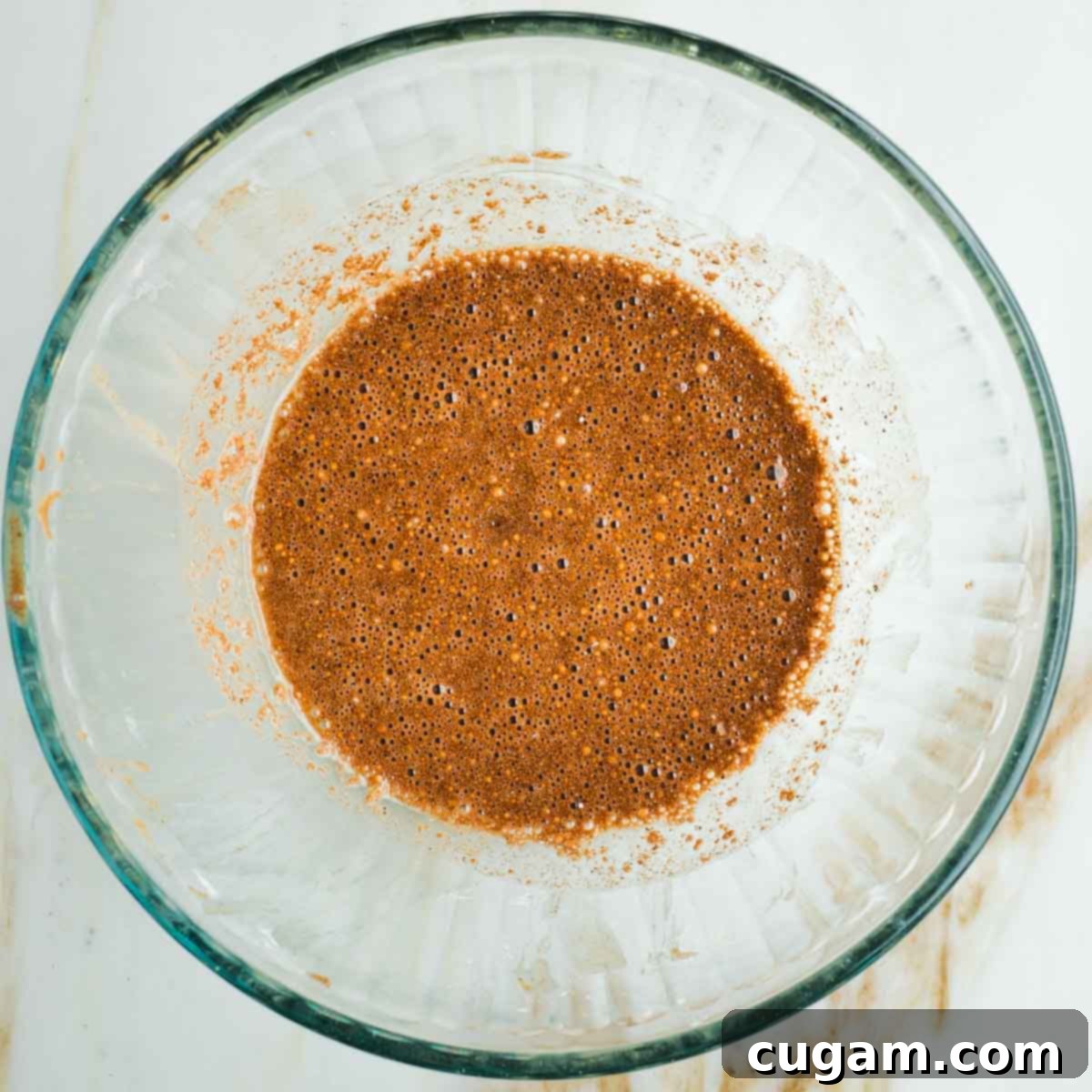 Brown spices combined with maple syrup and lemon juice to create a brown liquid, whisked until smooth.
