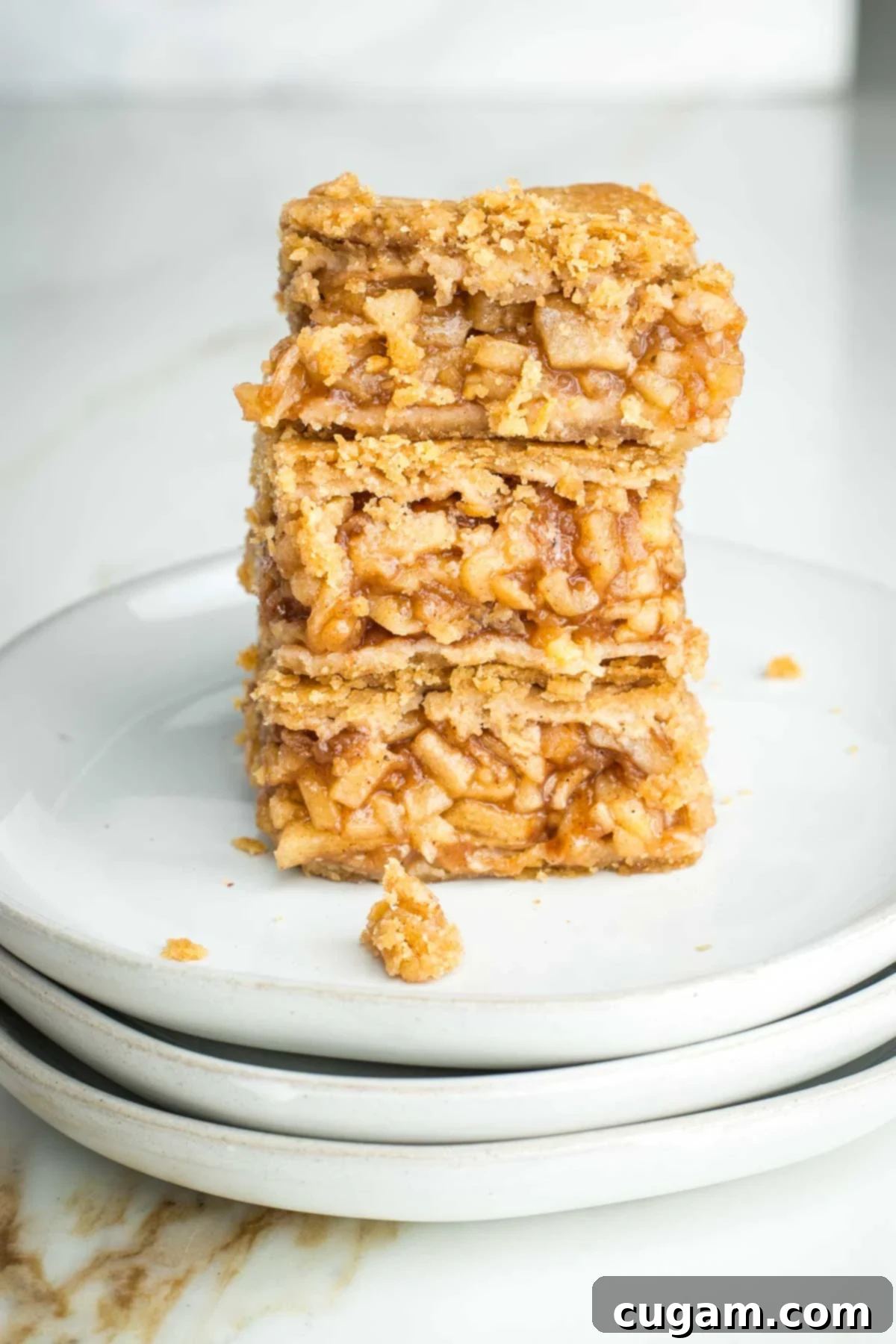 Three apple pie bars stacked on top of each other, showing the jammy apple filling and flaky crust inside, ready for freezing.