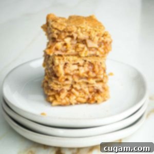 Stack of three apple pie bars with tiny pieces of apples in a thick jammy sauce, nestled between layers of flaky vegan crust.
